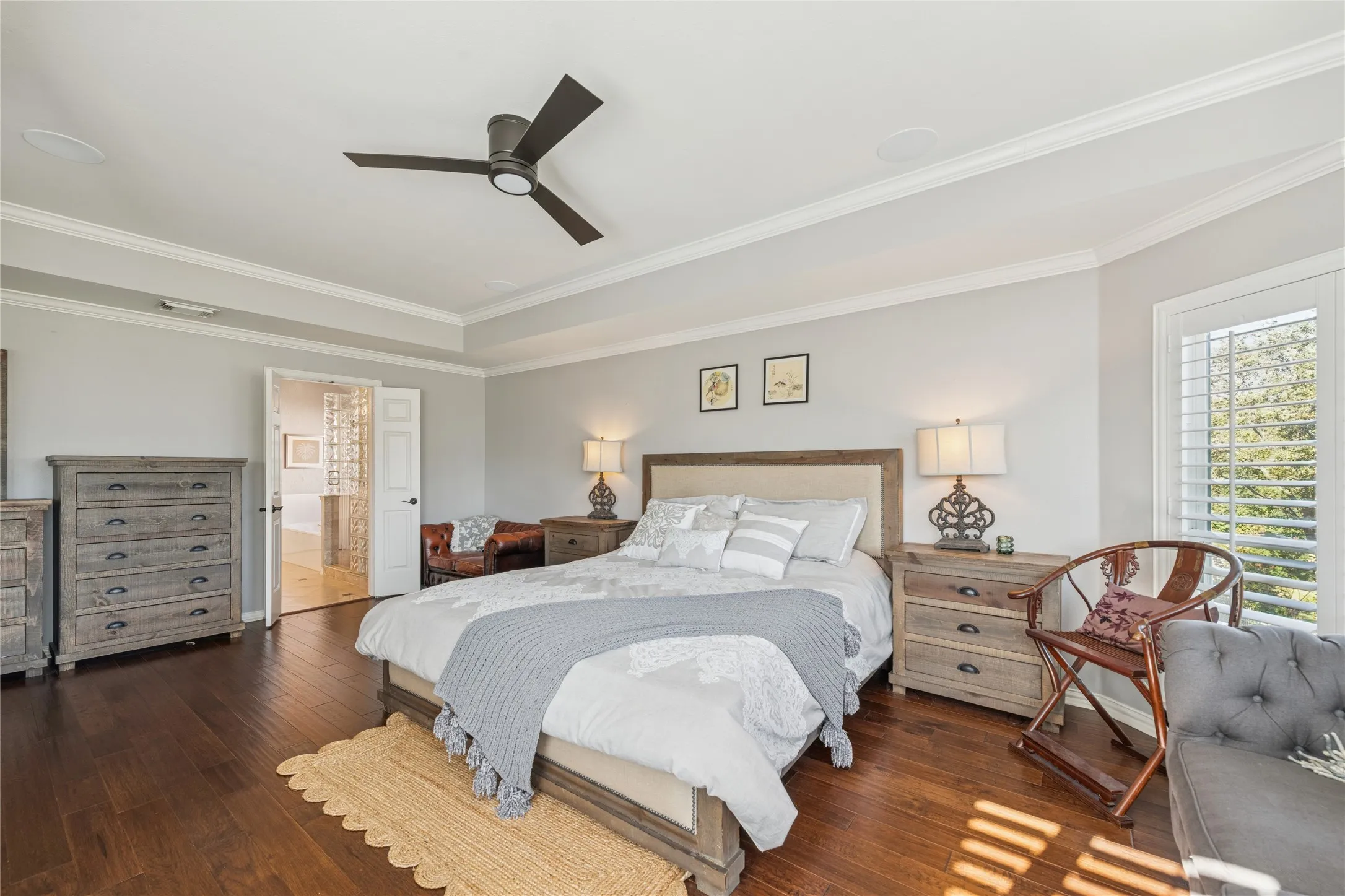 Bedroom with dark wood-type flooring, a ceiling fan, crown molding, and ensuite bathroom