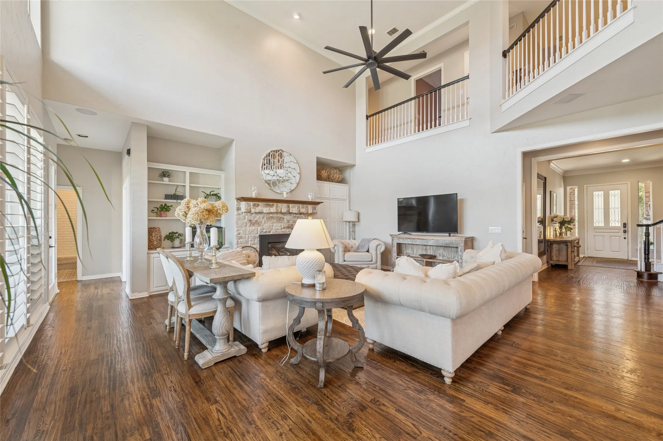 Living room with a fireplace, built in shelves, dark wood-style flooring, a high ceiling, and recessed lighting