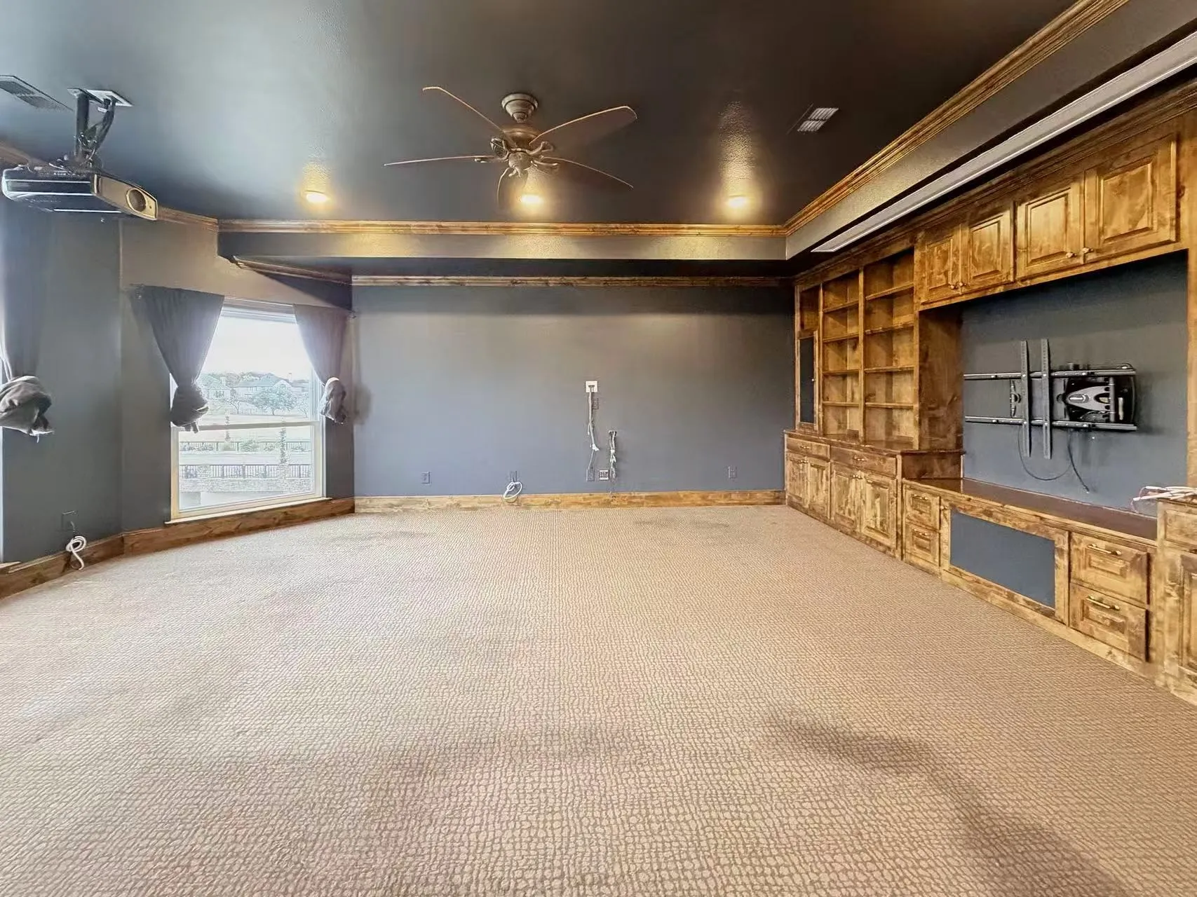 Home theater room with ceiling fan, carpet, and built in shelves
