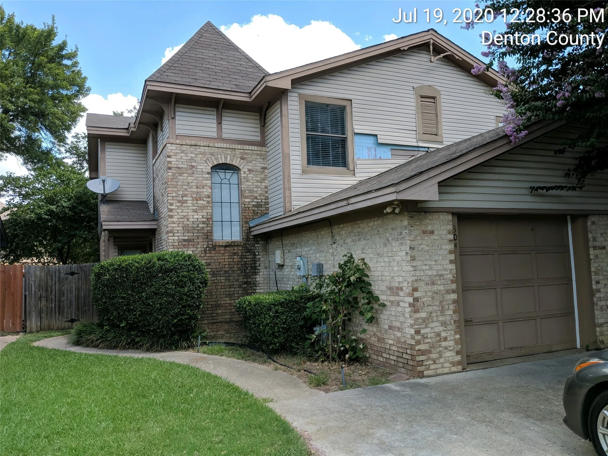 View of front of property with an attached garage, brick siding, and roof with shingles