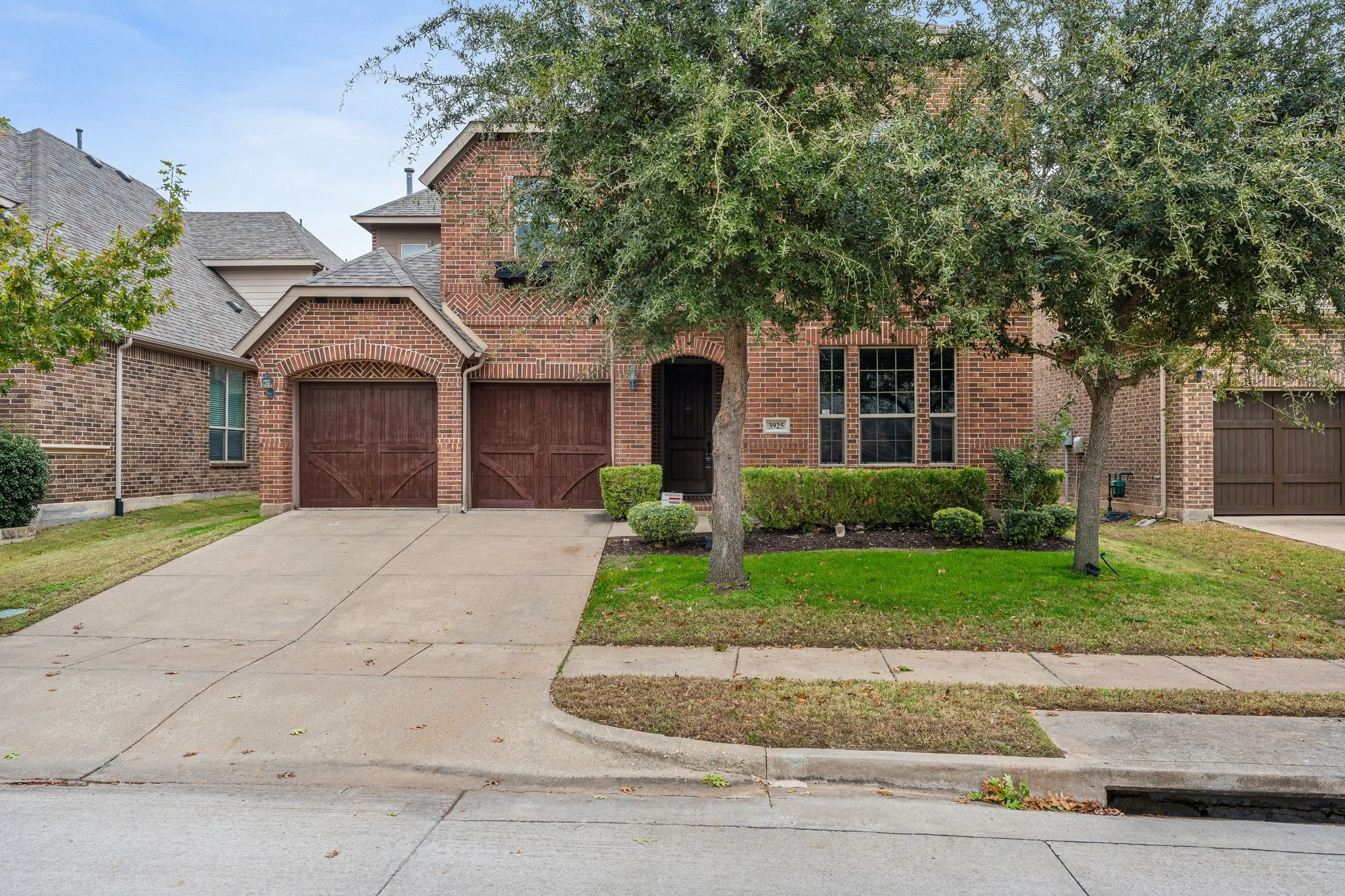 View of front facade featuring a front lawn, driveway, brick siding, and roof with shingles