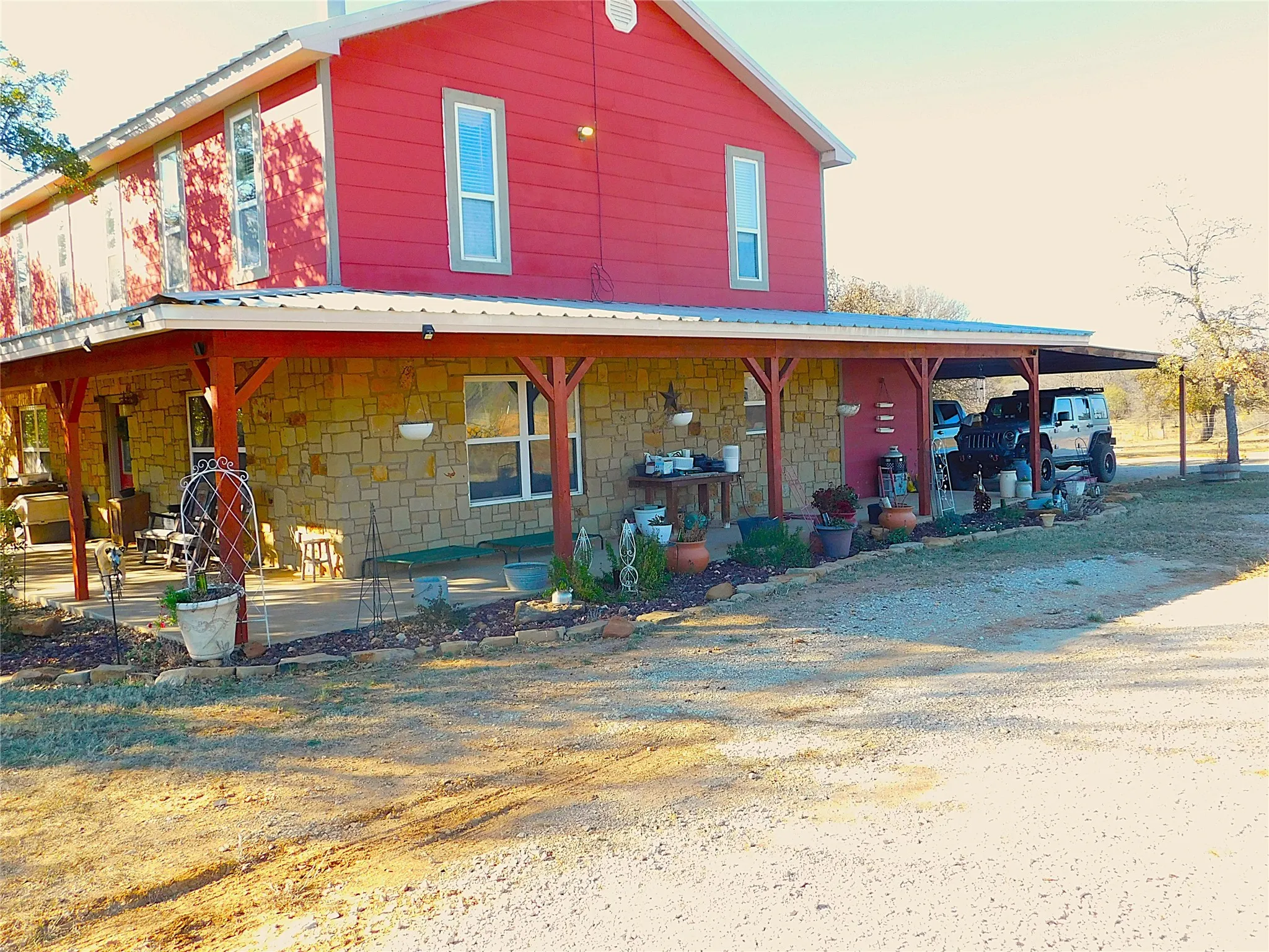 Farmhouse with stone siding, covered porch, and a metal roof