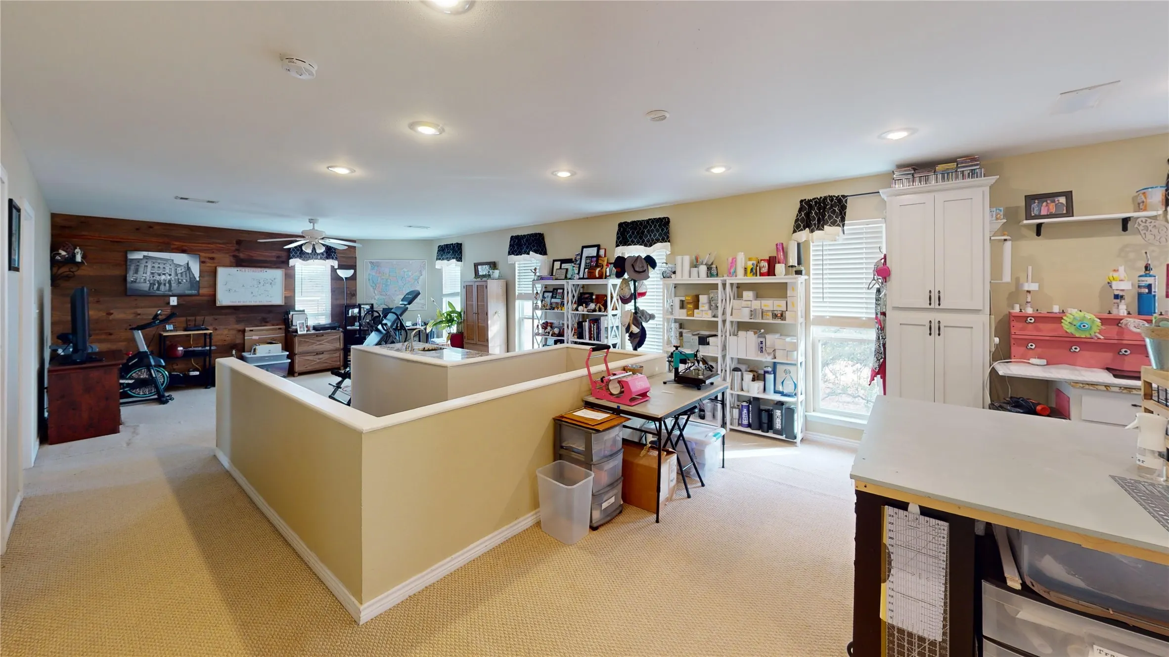 Kitchen featuring wood walls, light colored carpet, a ceiling fan, and white cabinetry