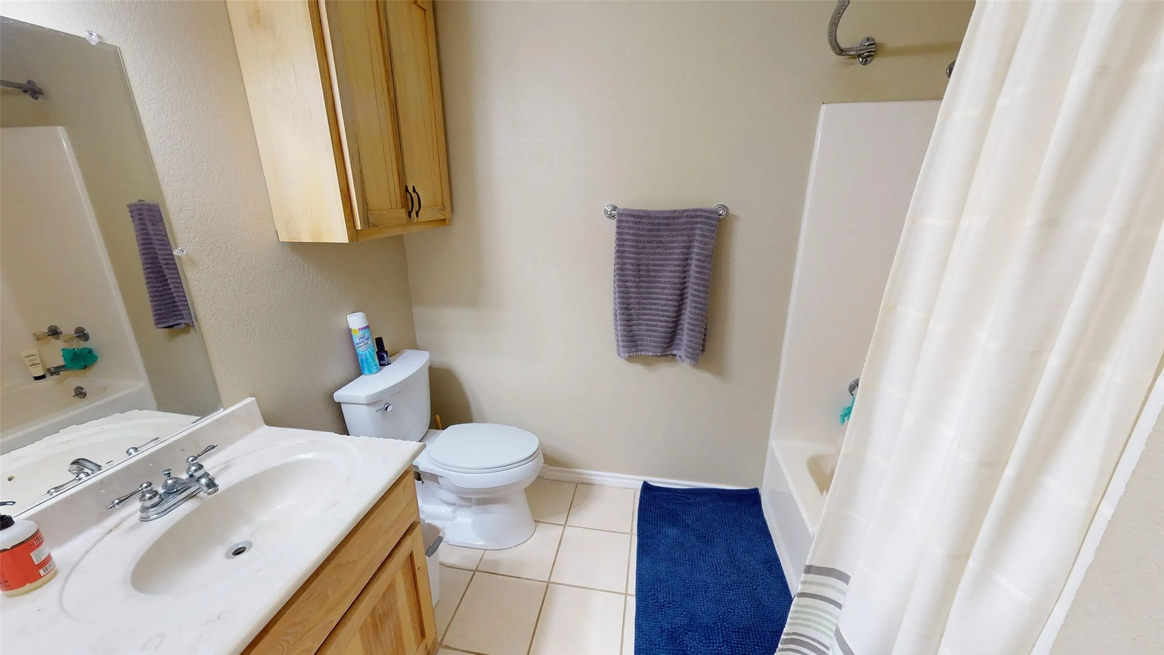 Bathroom featuring shower / tub combo, vanity, and light tile patterned floors