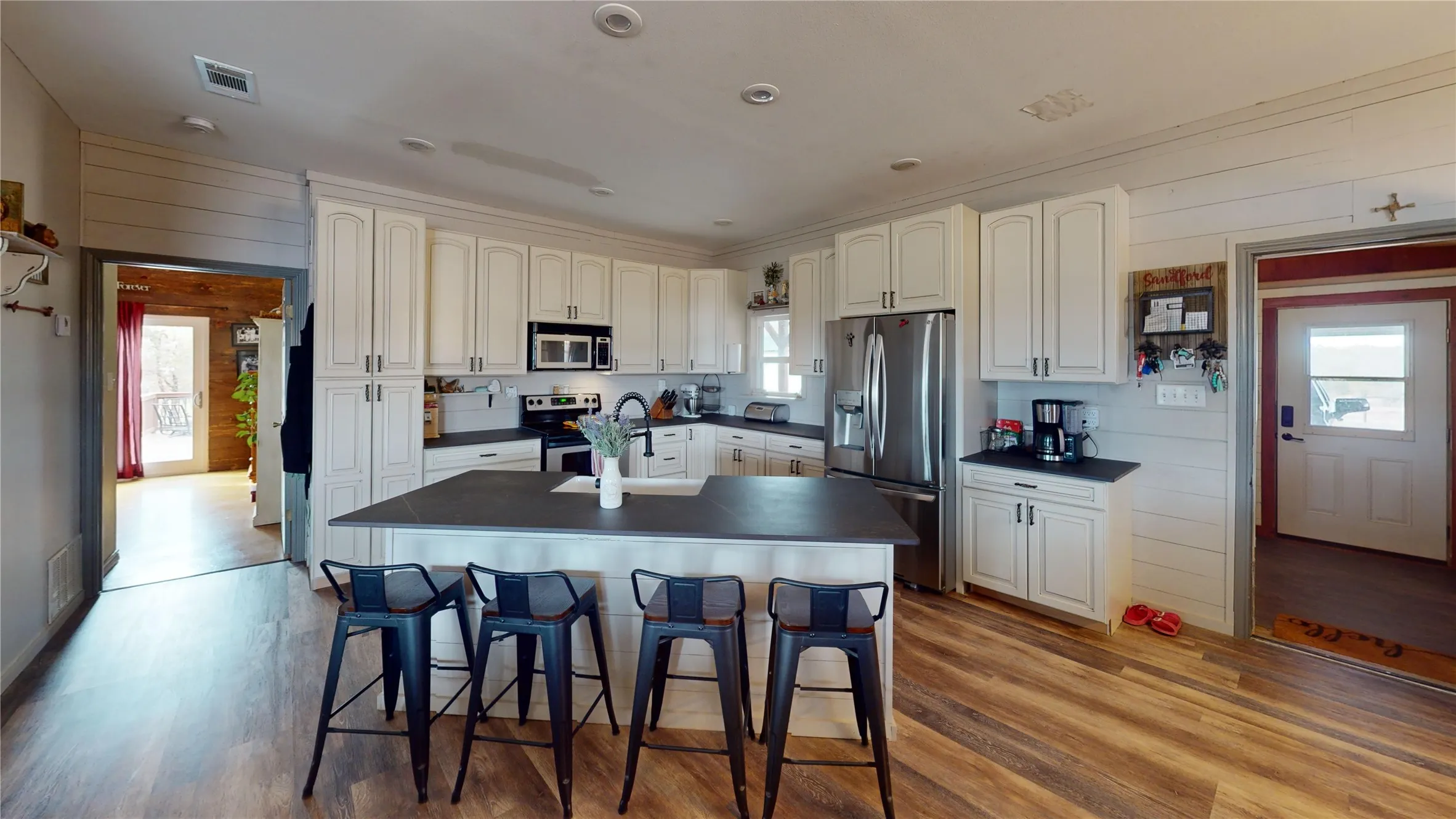 Kitchen featuring wooden walls, dark countertops, appliances with stainless steel finishes, a kitchen breakfast bar, and light wood-style floors