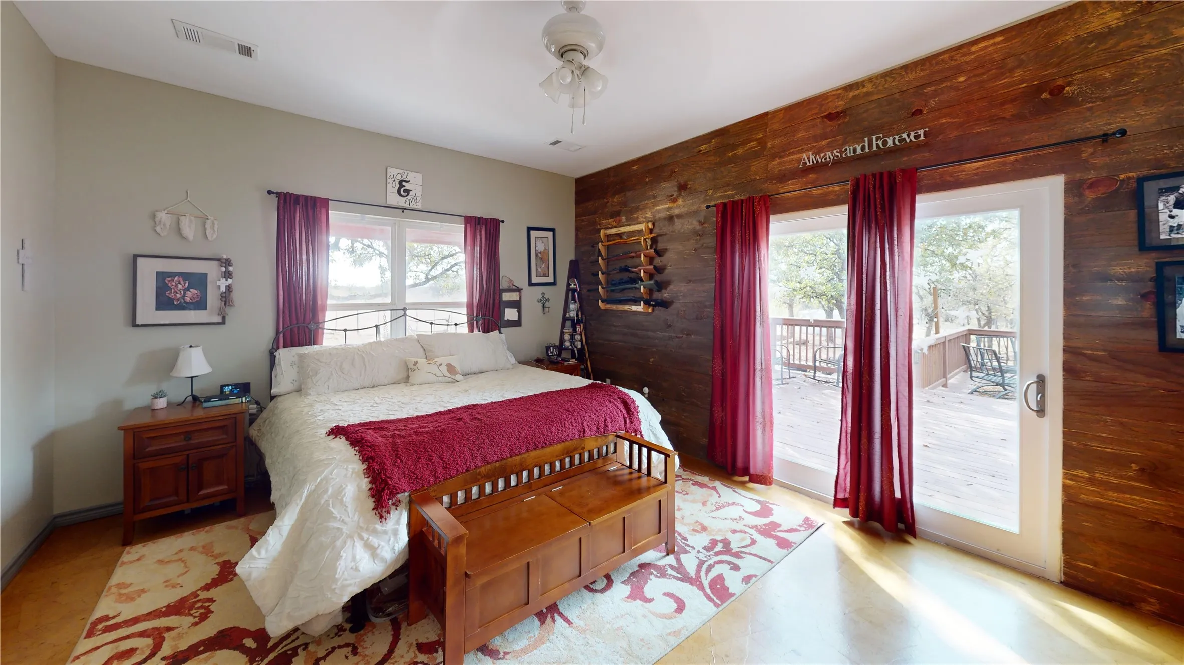 Bedroom with wooden walls, access to exterior, a ceiling fan, and an accent wall