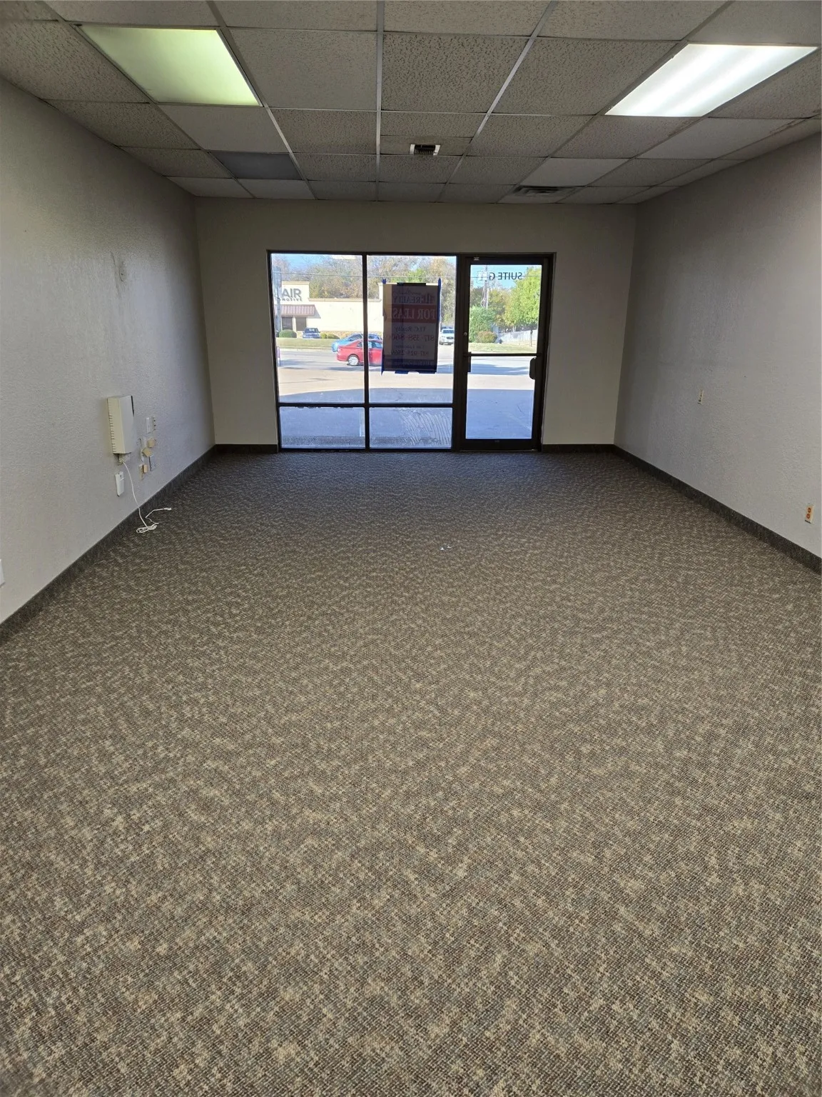Carpeted spare room featuring a paneled ceiling