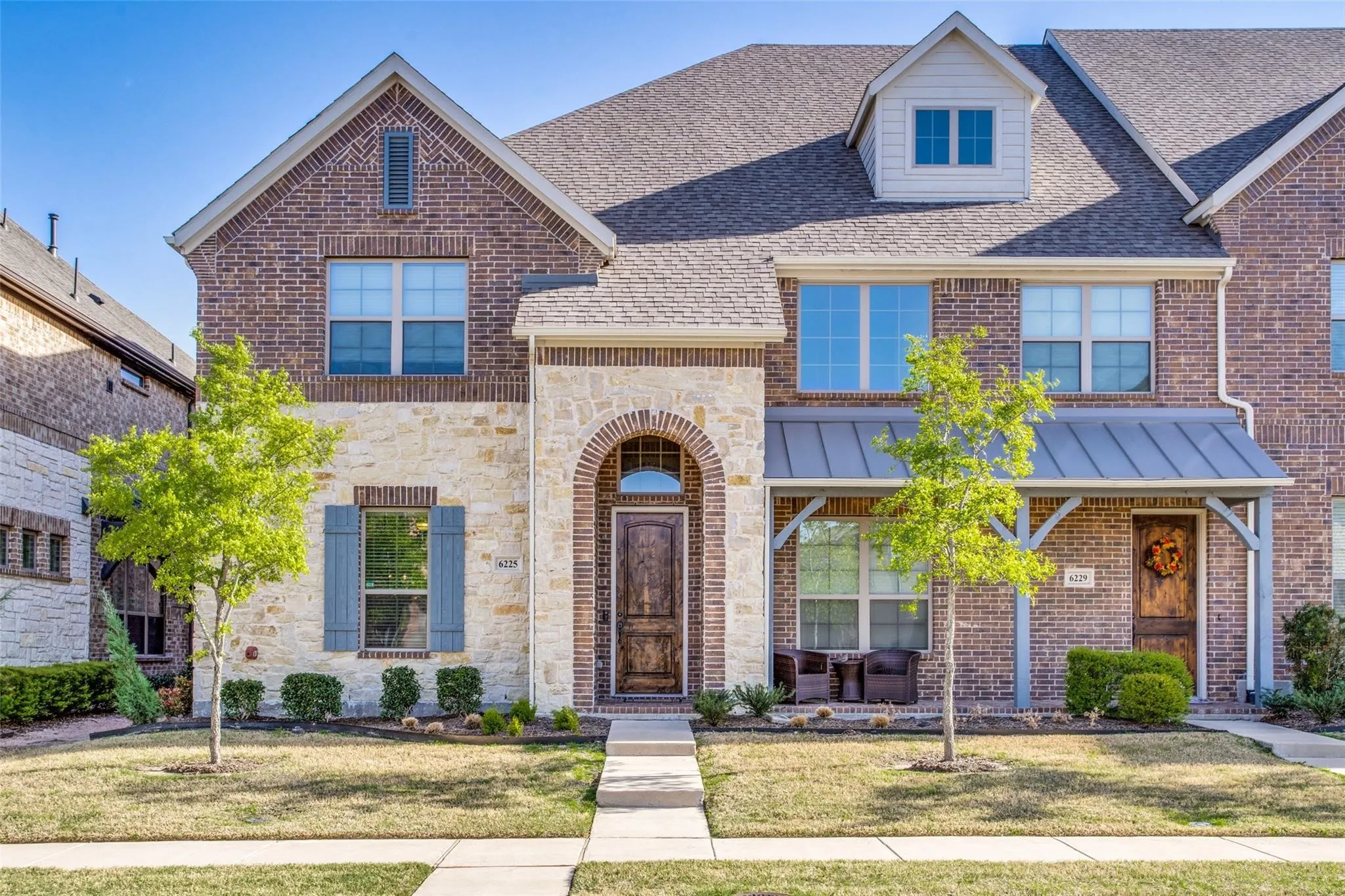 View of front facade with a front yard, stone siding, roof with shingles, and brick siding