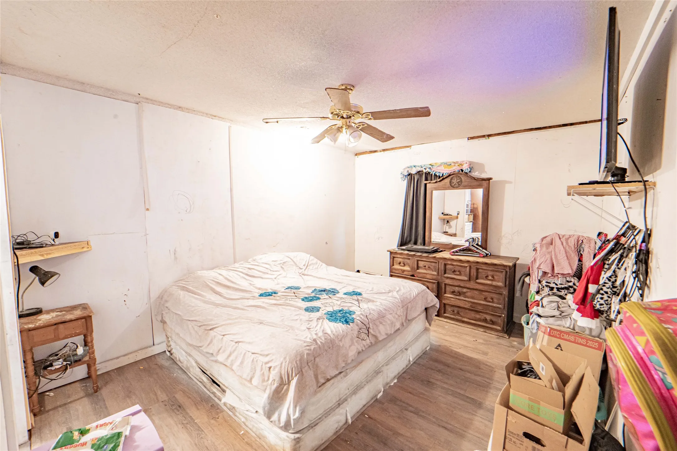 Bedroom featuring a textured ceiling, wood finished floors, and a ceiling fan