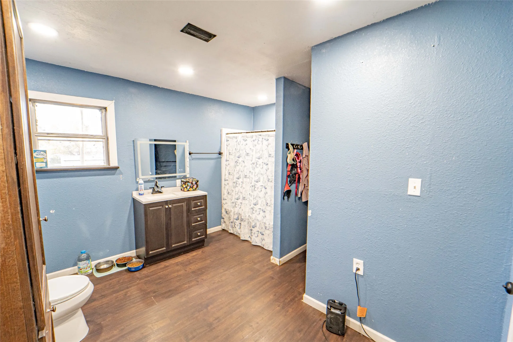 Bathroom with a shower with curtain, a textured wall, vanity, dark wood finished floors, and recessed lighting