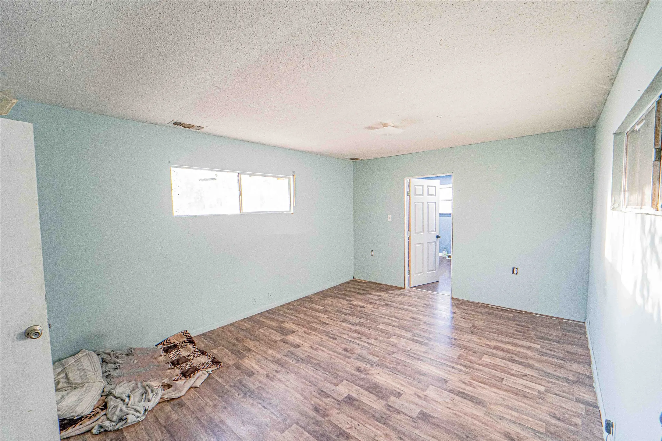 Empty room with wood finished floors and a textured ceiling