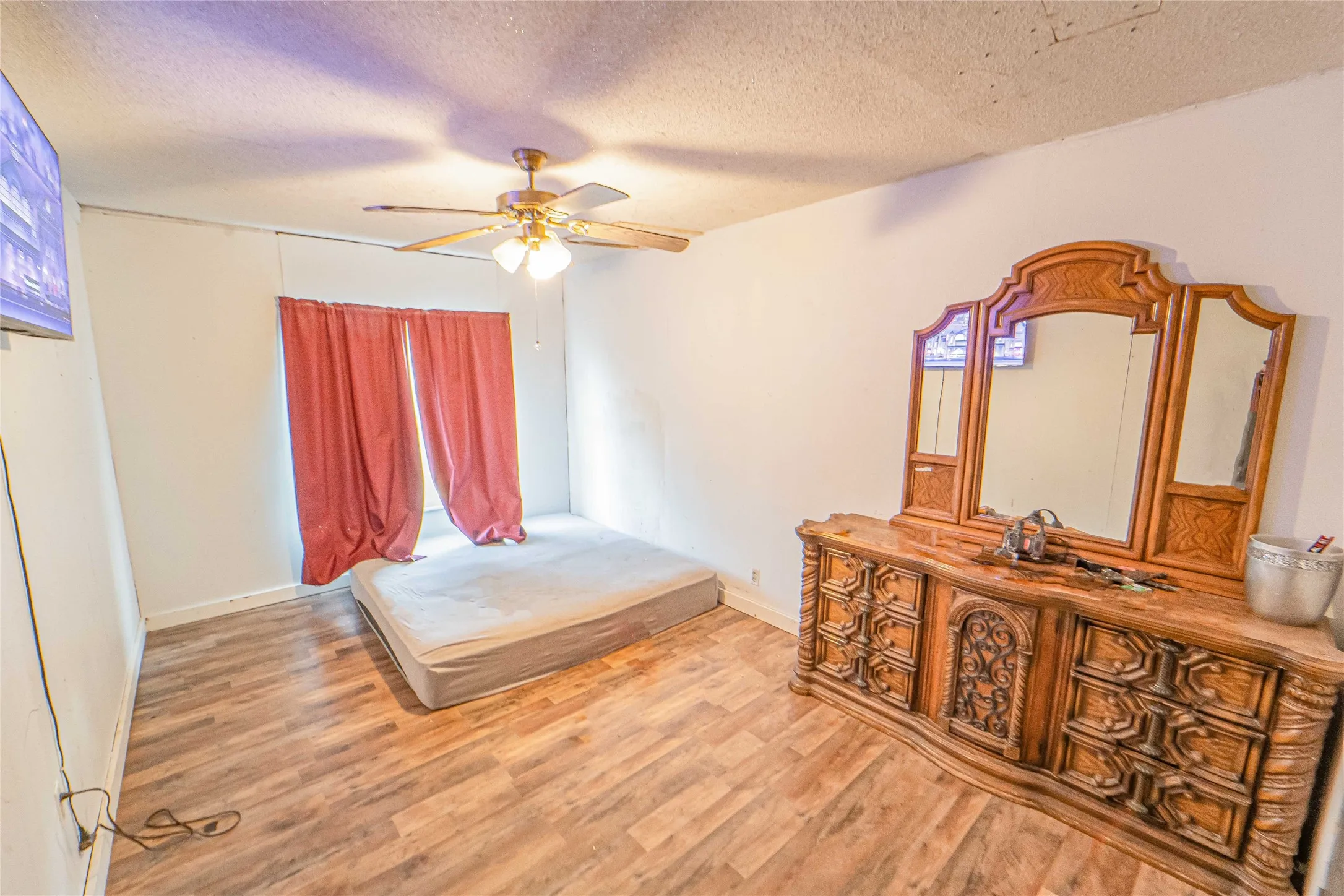 Bedroom featuring a textured ceiling, light wood-style floors, and a ceiling fan