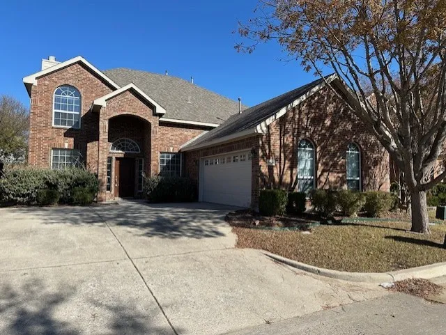 View of front of home with driveway, a garage, a chimney, and brick siding