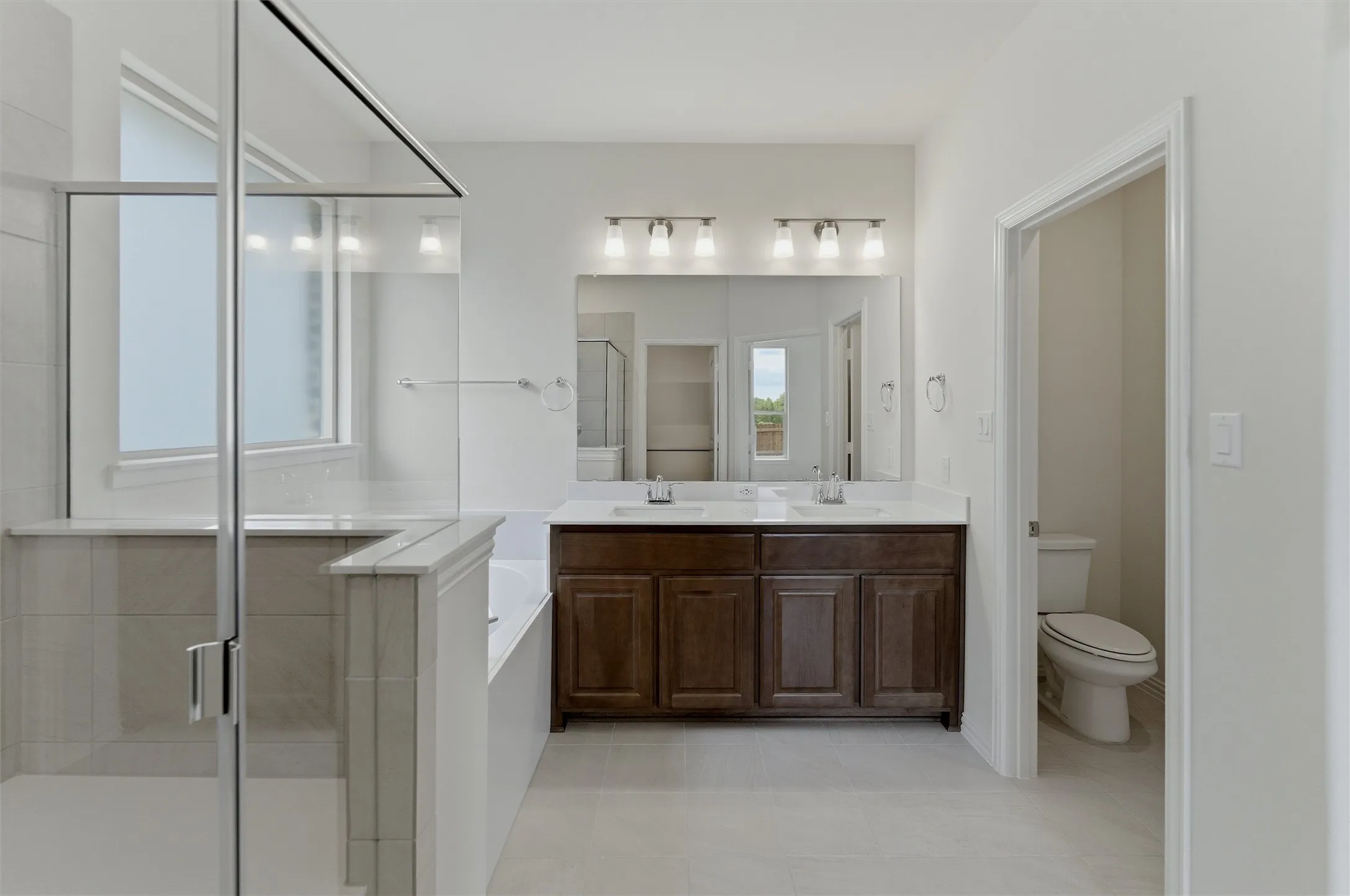 Bathroom featuring a dual vanity with dark wood cabinetry and a white countertop, two undermount sinks, and an expansive mirror