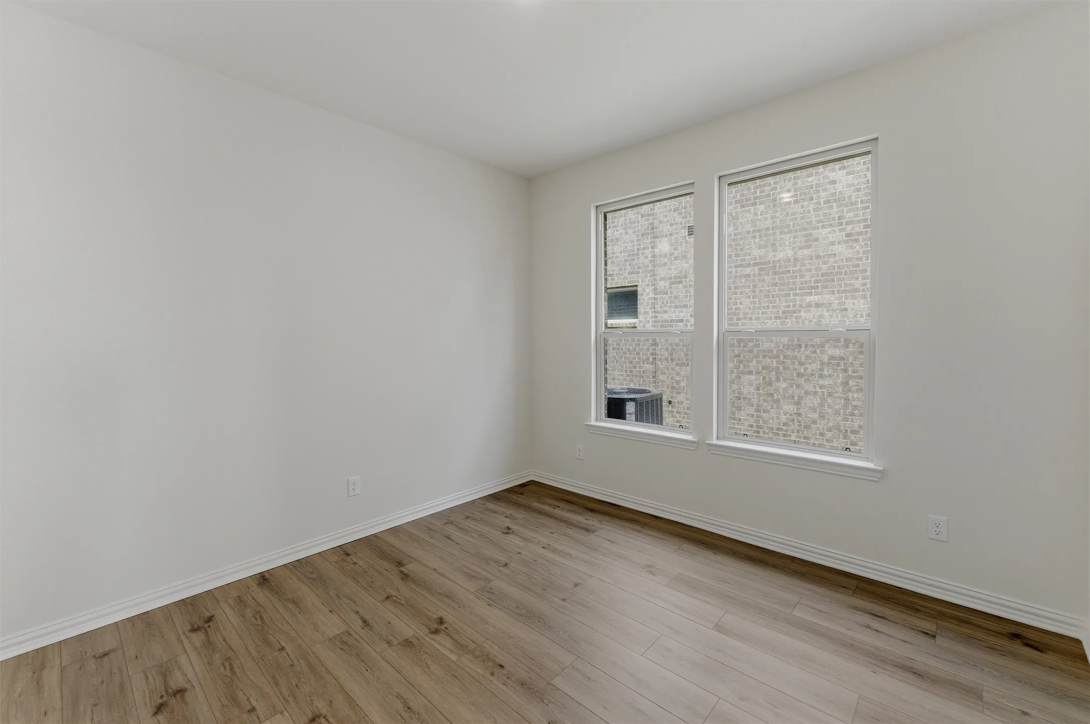 Spacious room featuring wood-finish flooring and dual windows