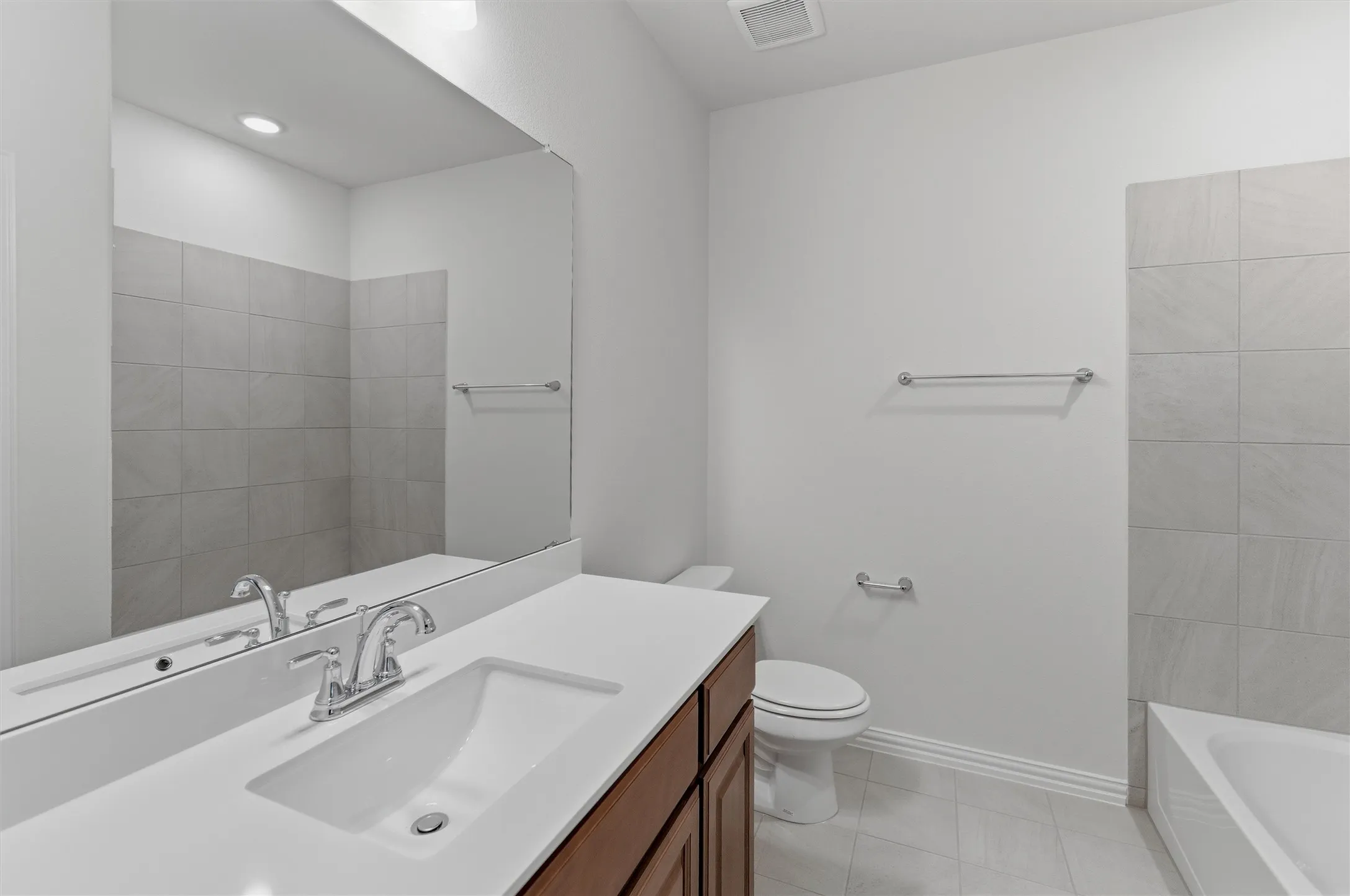 Bathroom featuring a rectangular undermount sink with a chrome faucet, a wood-finish vanity, and a large wall-mounted mirror