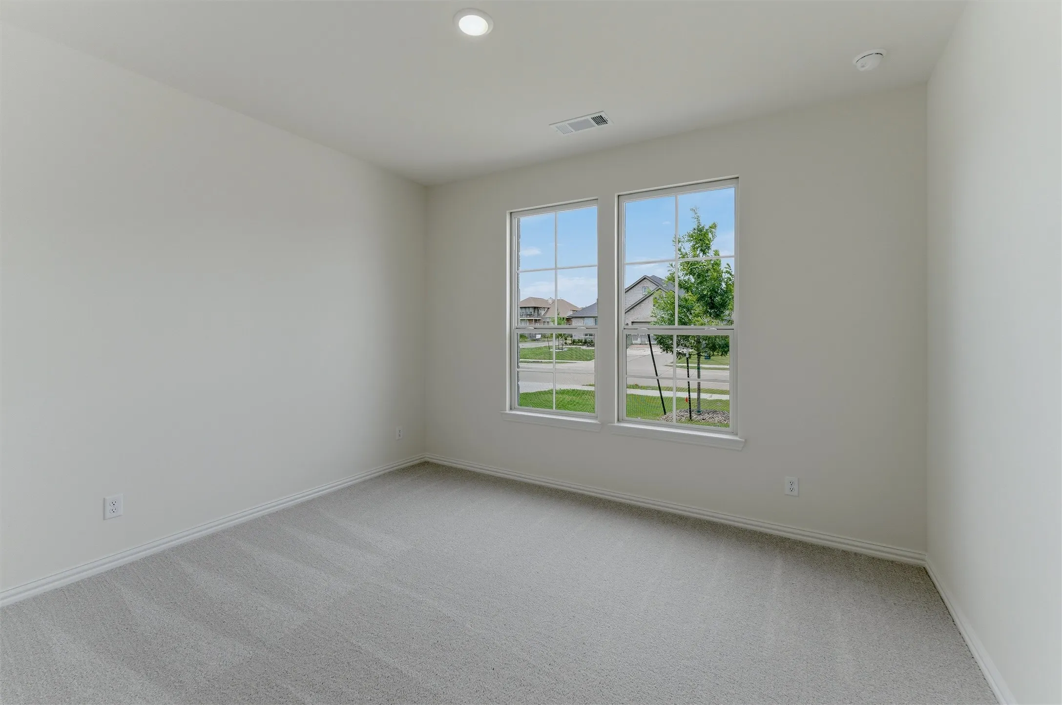 Bright interior space featuring light-colored walls and grey carpet flooring