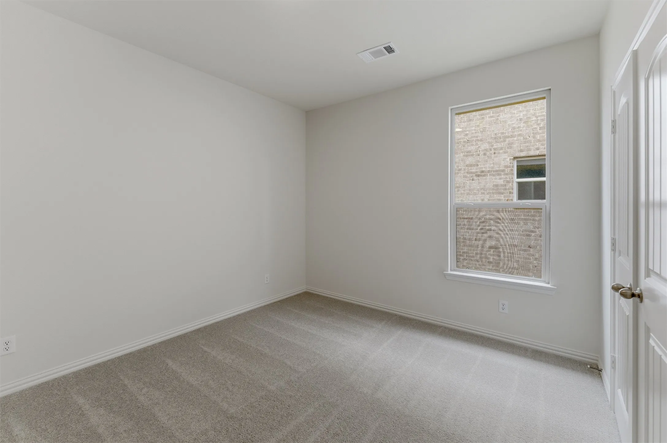 Spacious room featuring neutral carpeting, light-toned walls, and a white trim package