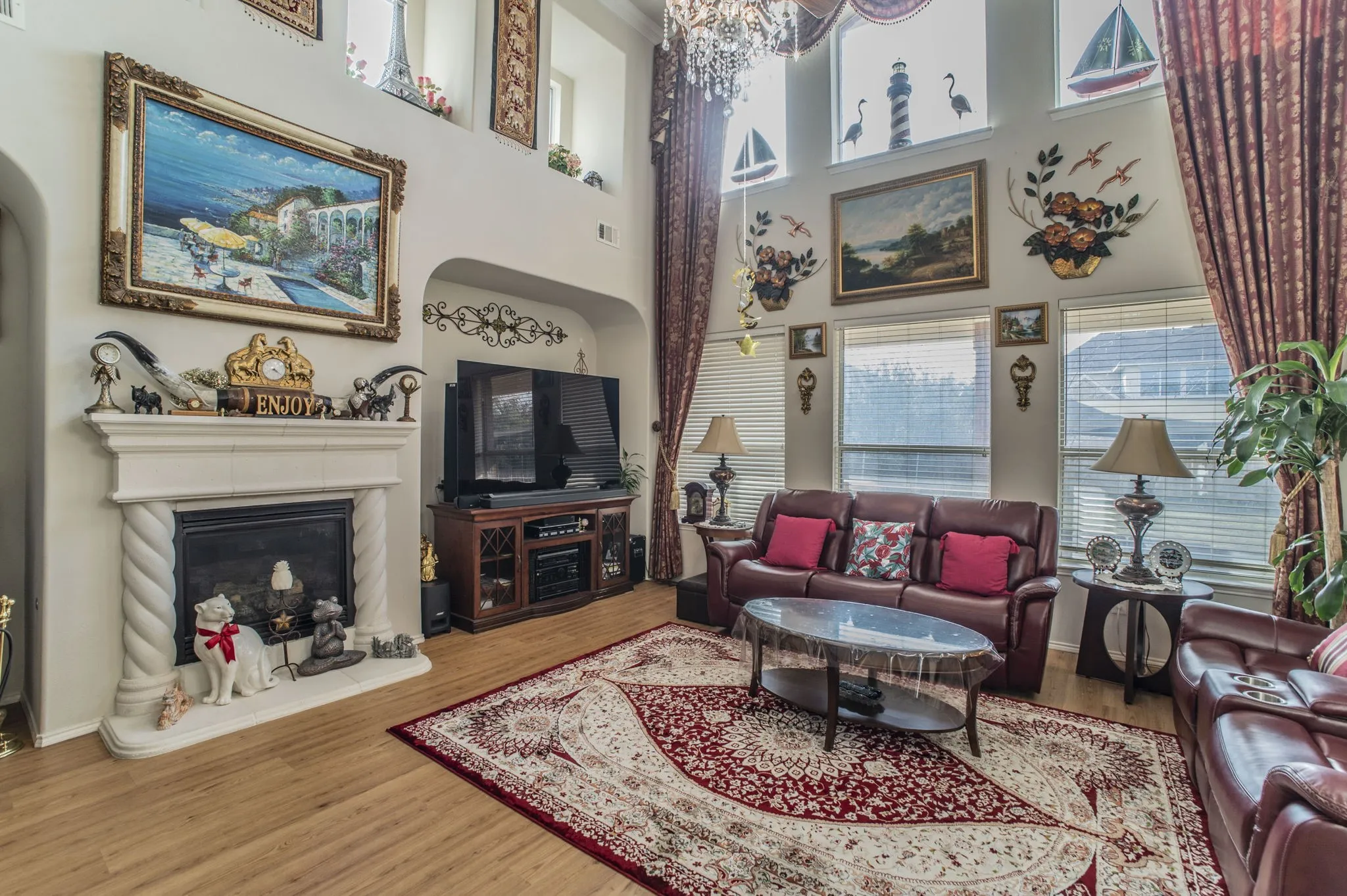 Living room with a glass covered fireplace, wood finished floors, a high ceiling, and a chandelier