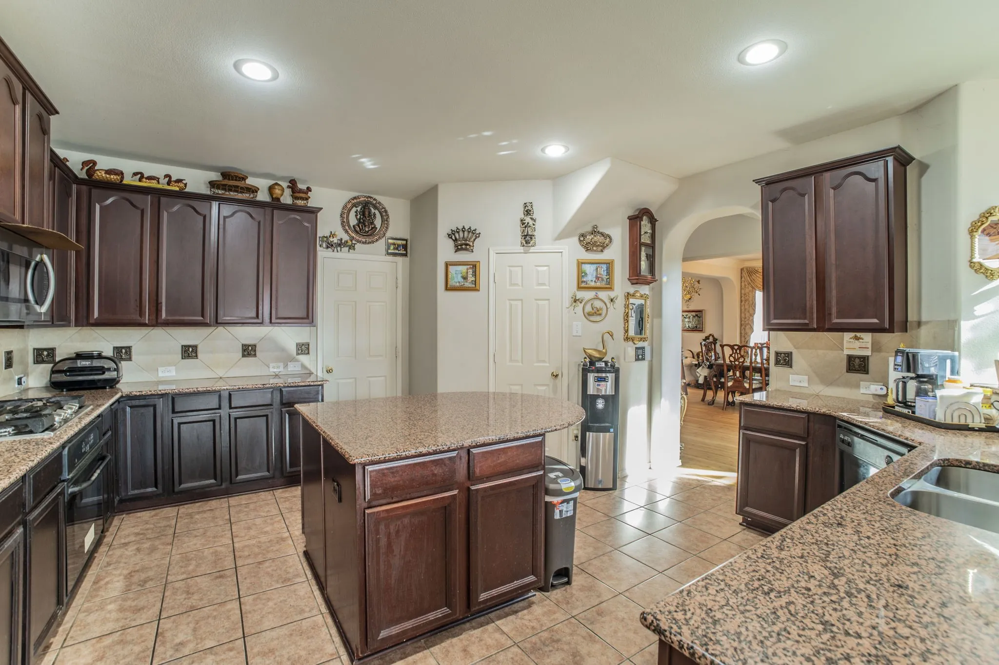 Kitchen featuring tasteful backsplash, arched walkways, dark brown cabinetry, and recessed lighting