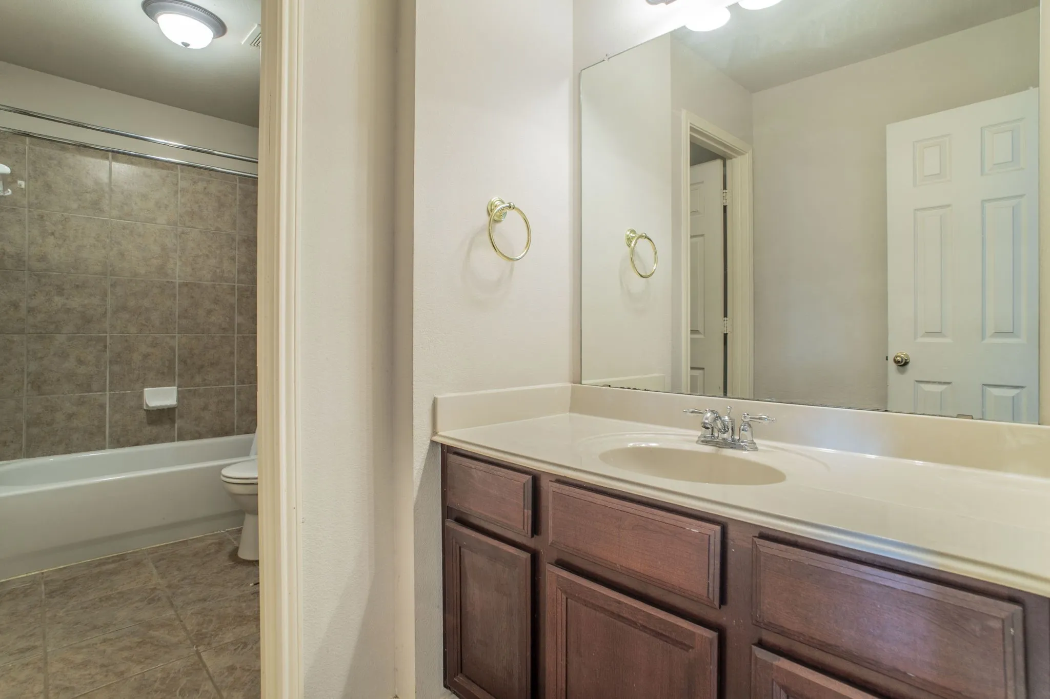 Bathroom with vanity, tub / shower combination, and light tile patterned floors