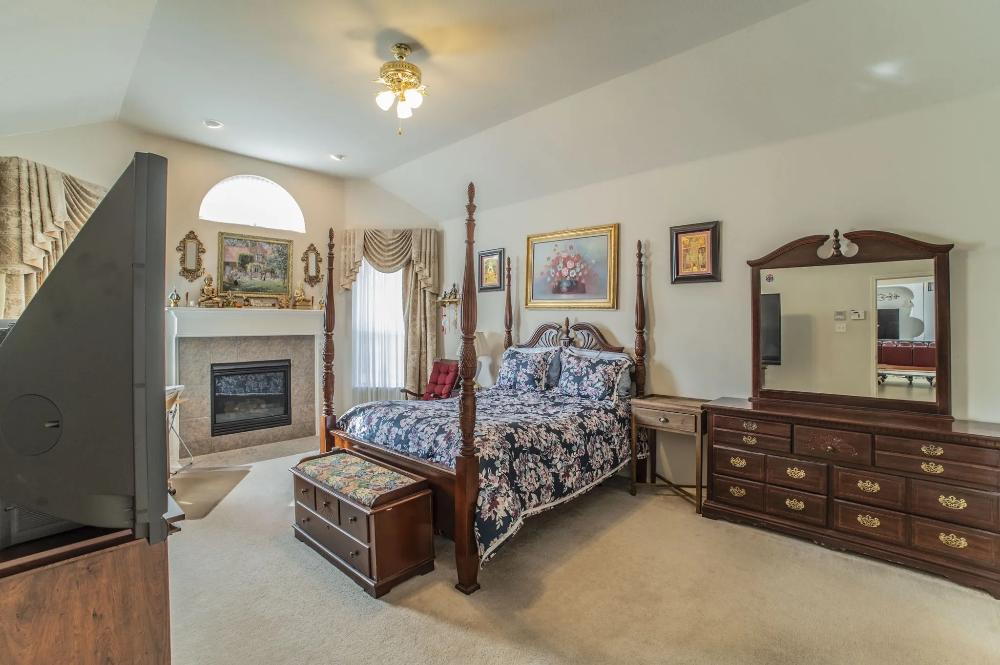 Bedroom featuring ceiling fan, light carpet, lofted ceiling, and a glass covered fireplace