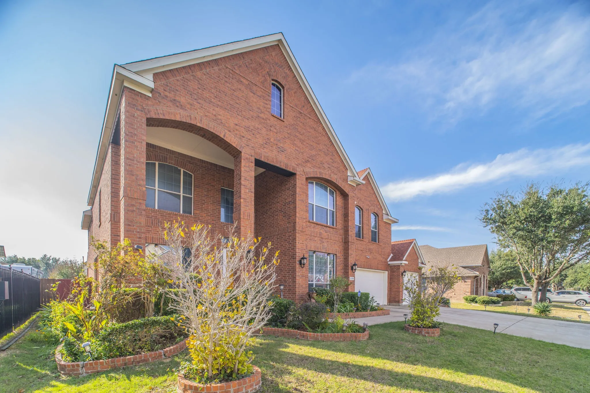 Traditional-style home featuring brick siding, driveway, a front lawn, and an attached garage