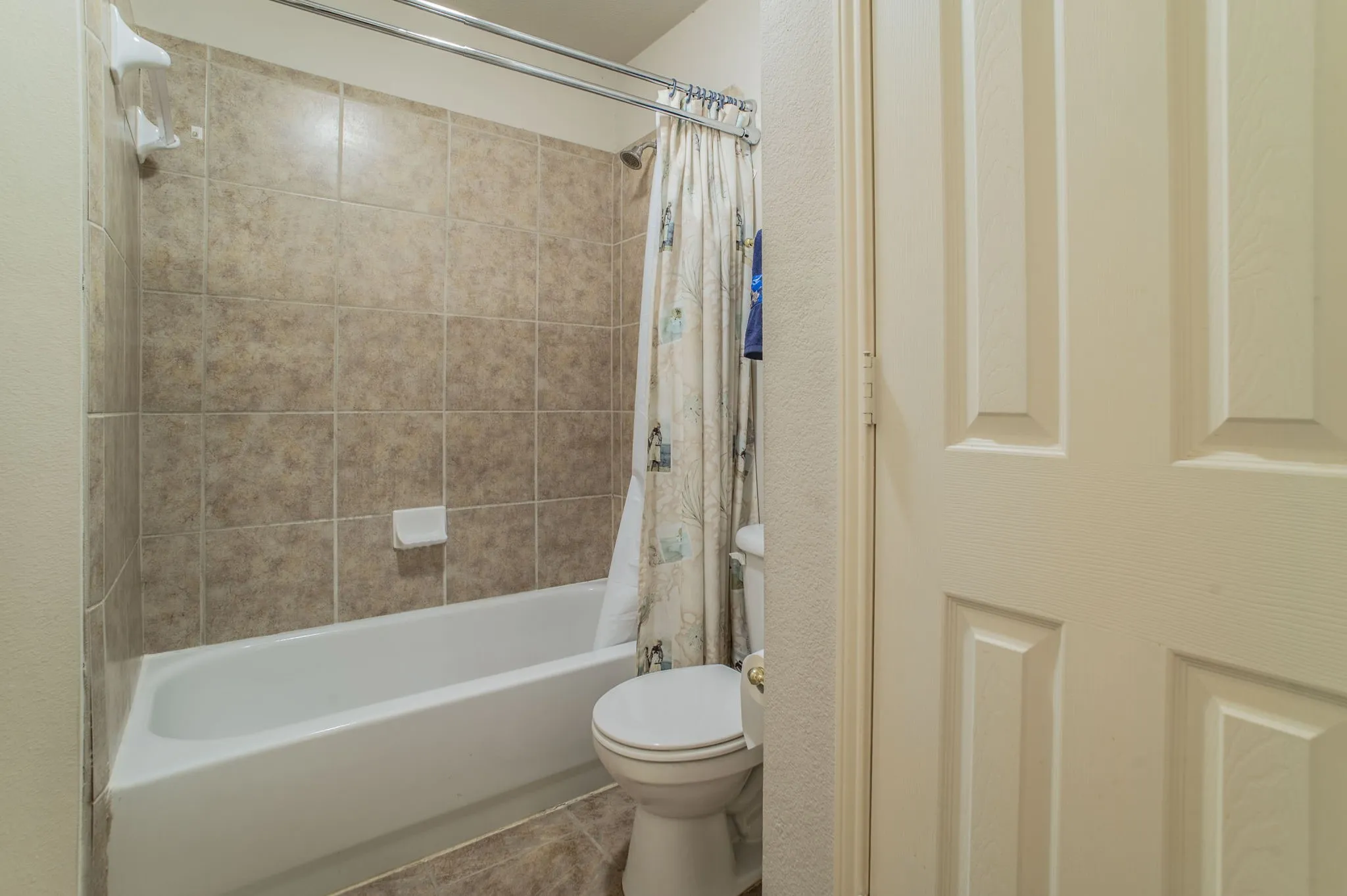 Bathroom with shower / bath combination with curtain and toilet