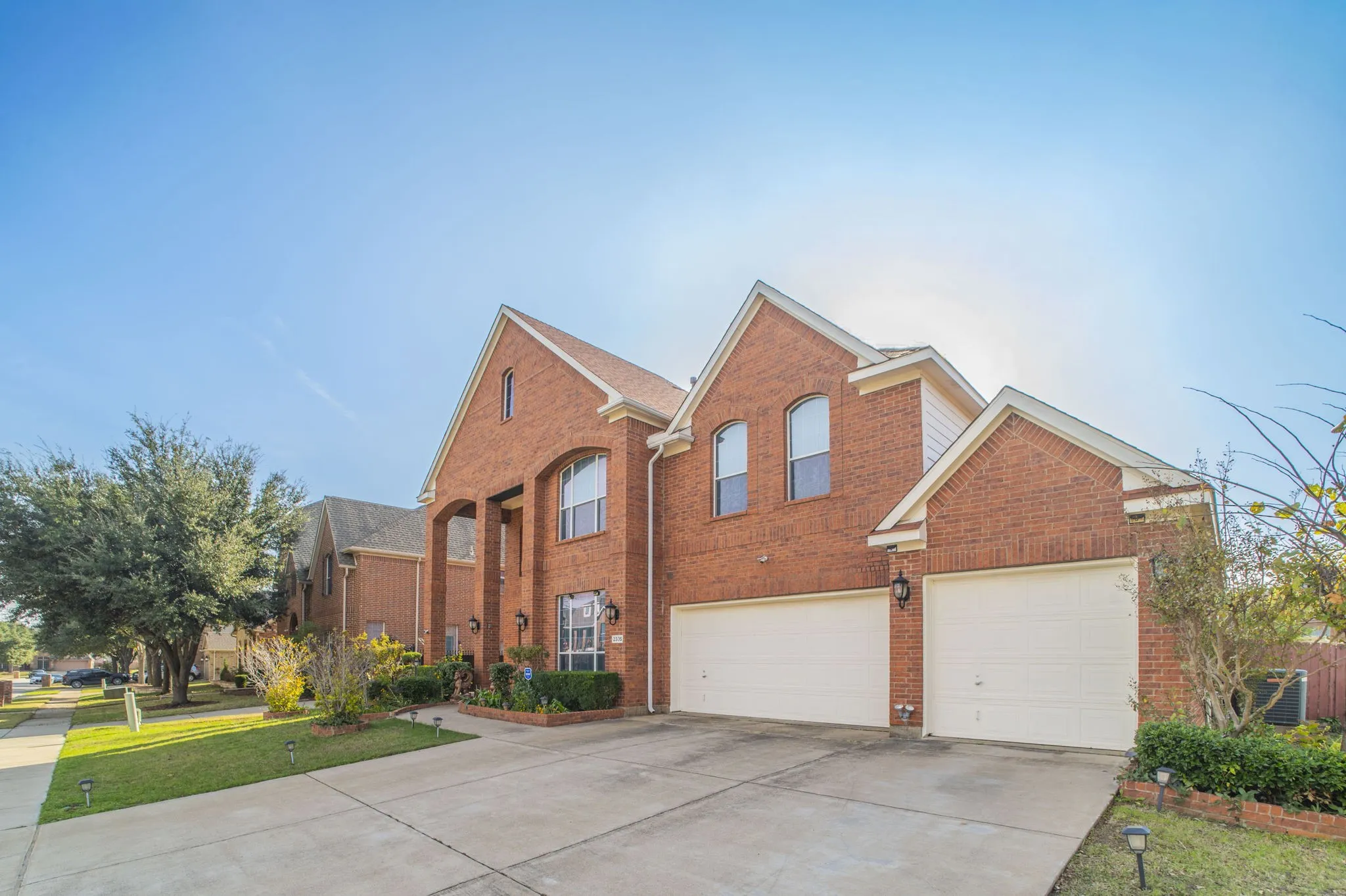 Traditional-style home with driveway, brick siding, an attached garage, and a front yard