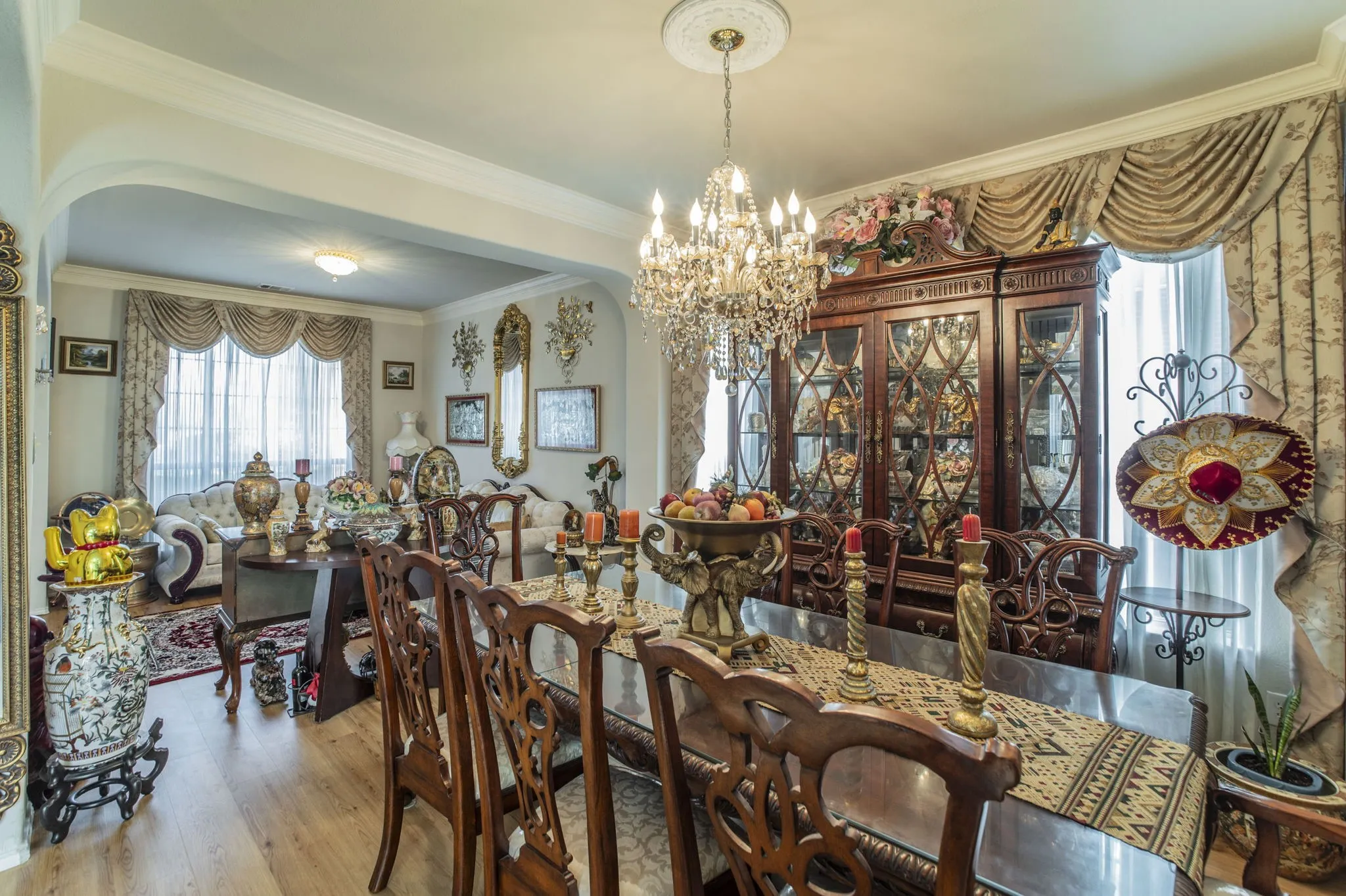 Dining space with crown molding, light wood finished floors, a chandelier, and arched walkways