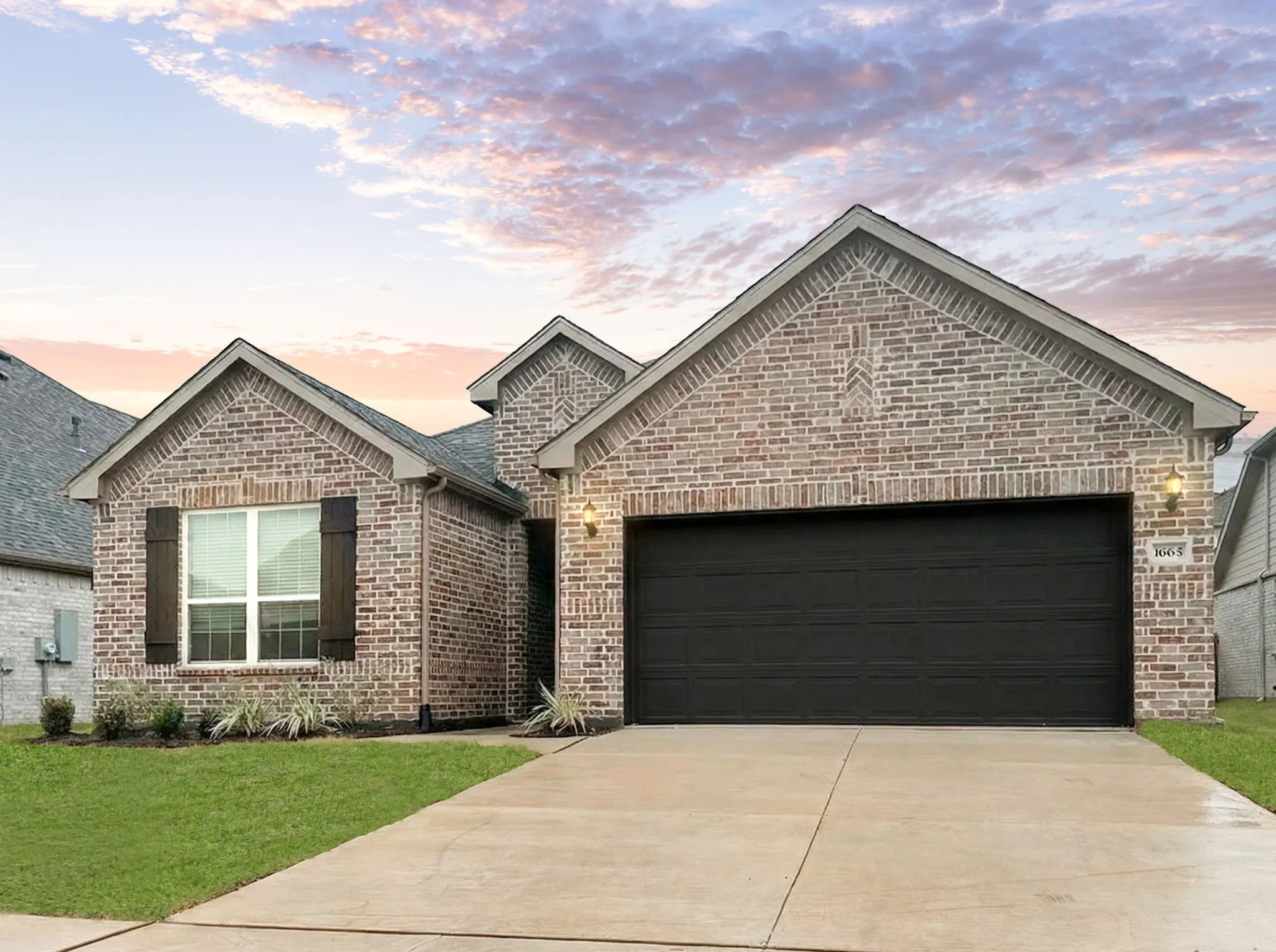 View of front of property with brick siding, an attached garage, concrete driveway, and a front yard