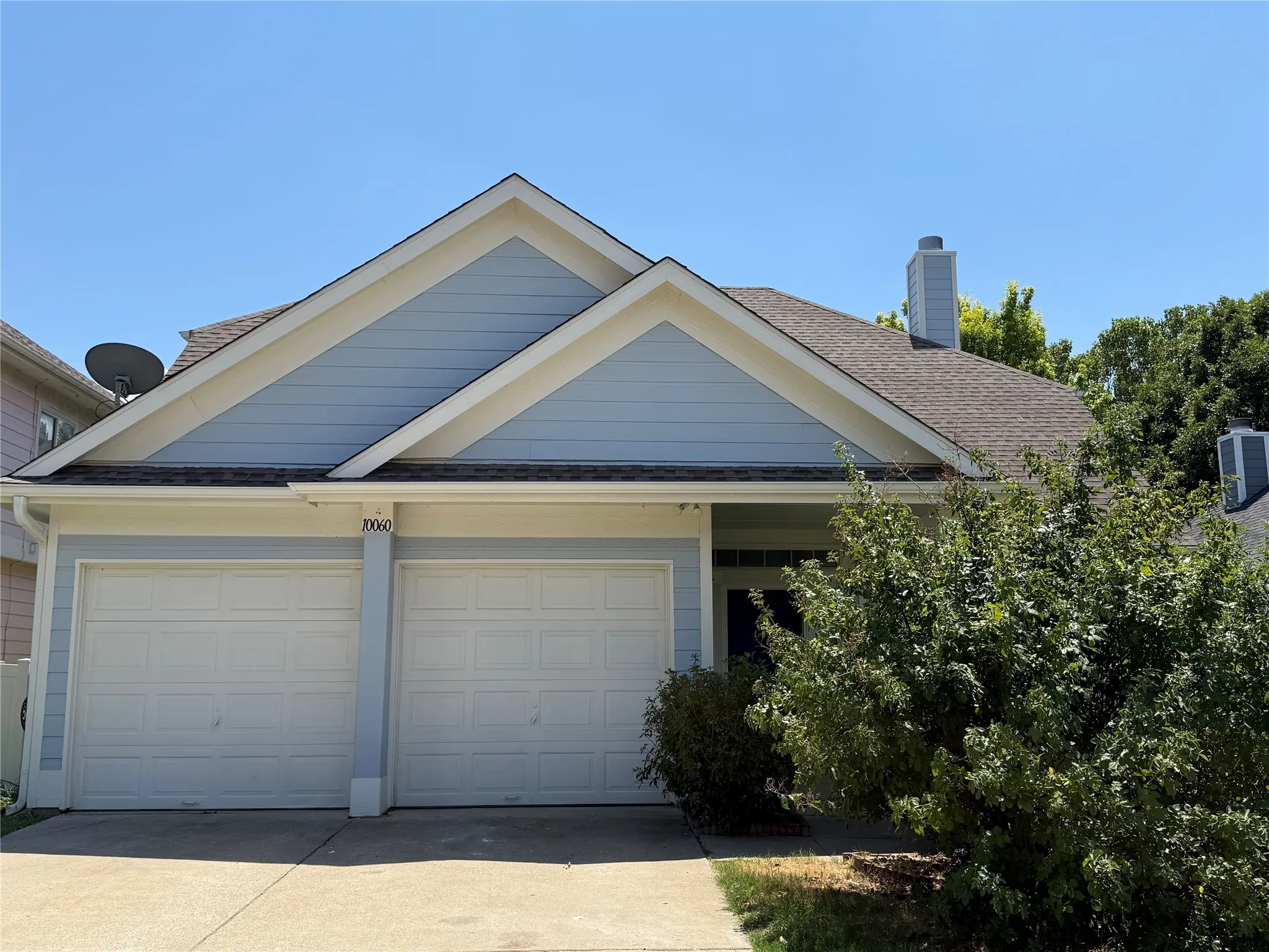 View of front of property with a shingled roof, driveway, a chimney, and an attached garage