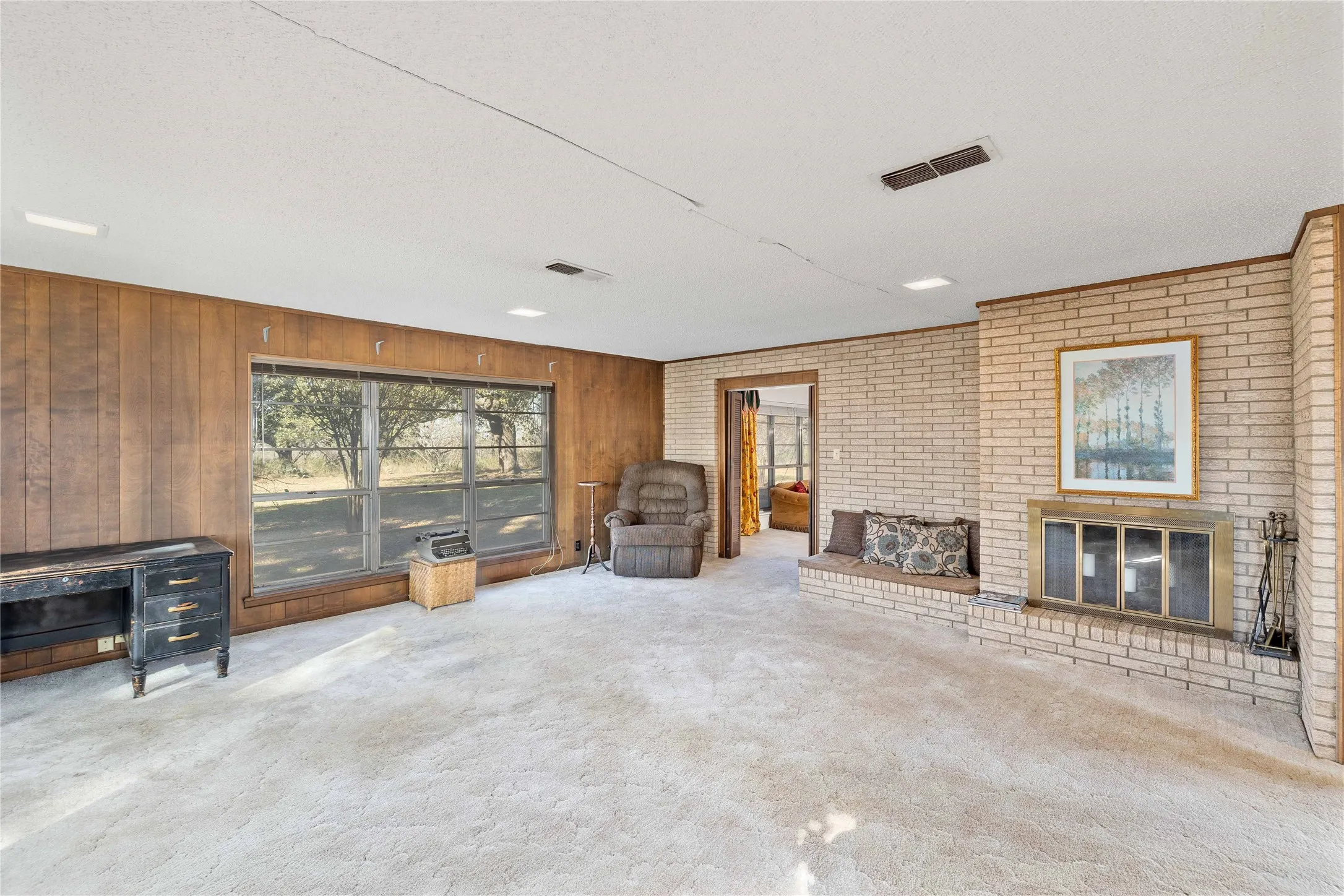 Den with brick wood-burning fireplace