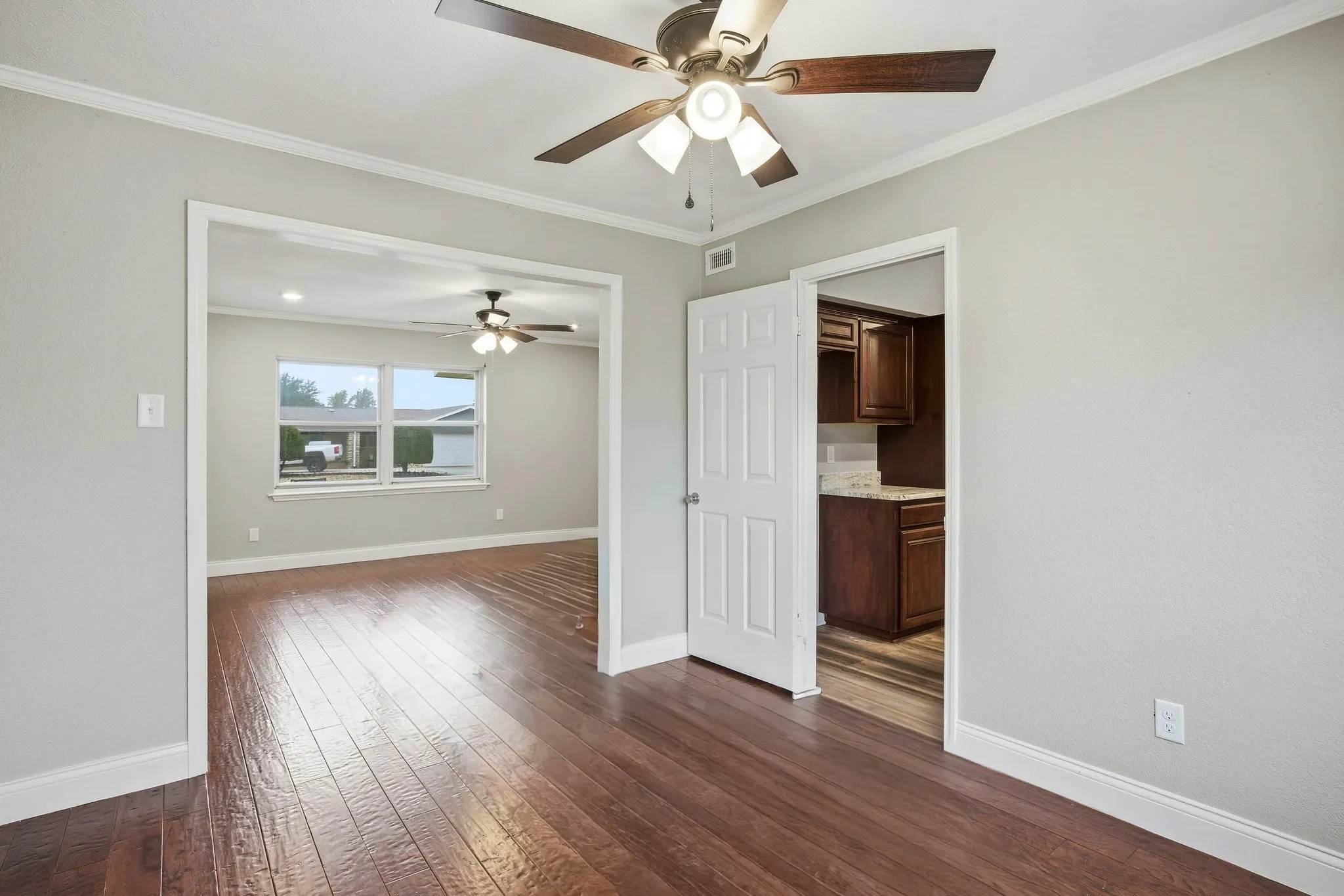 Dining room with crown molding, dark wood-style flooring, and a ceiling fan.