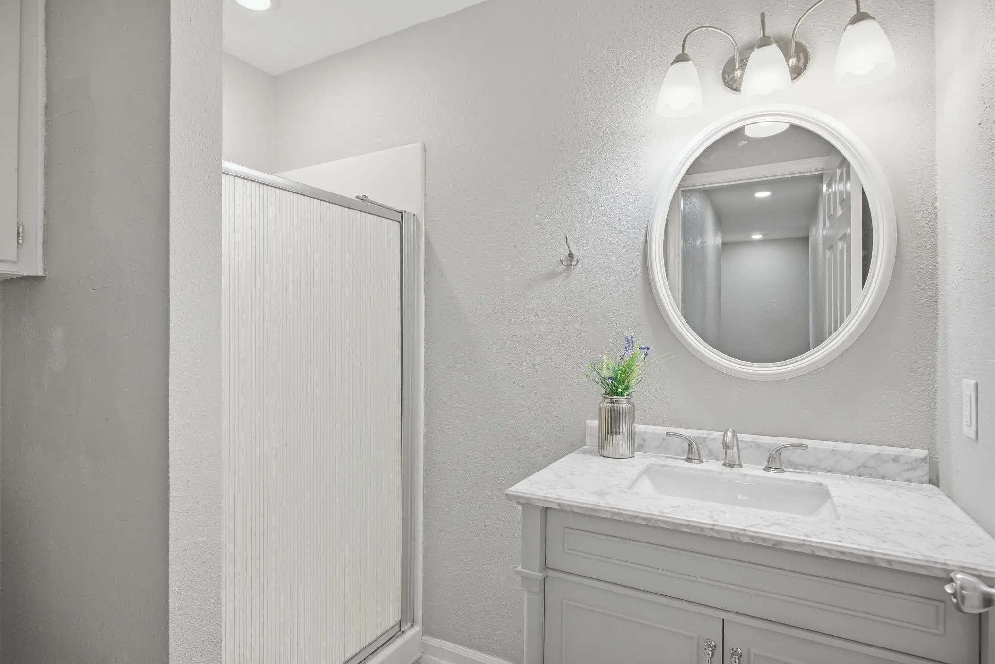 Full bathroom featuring vanity, a stall shower, and a textured wall