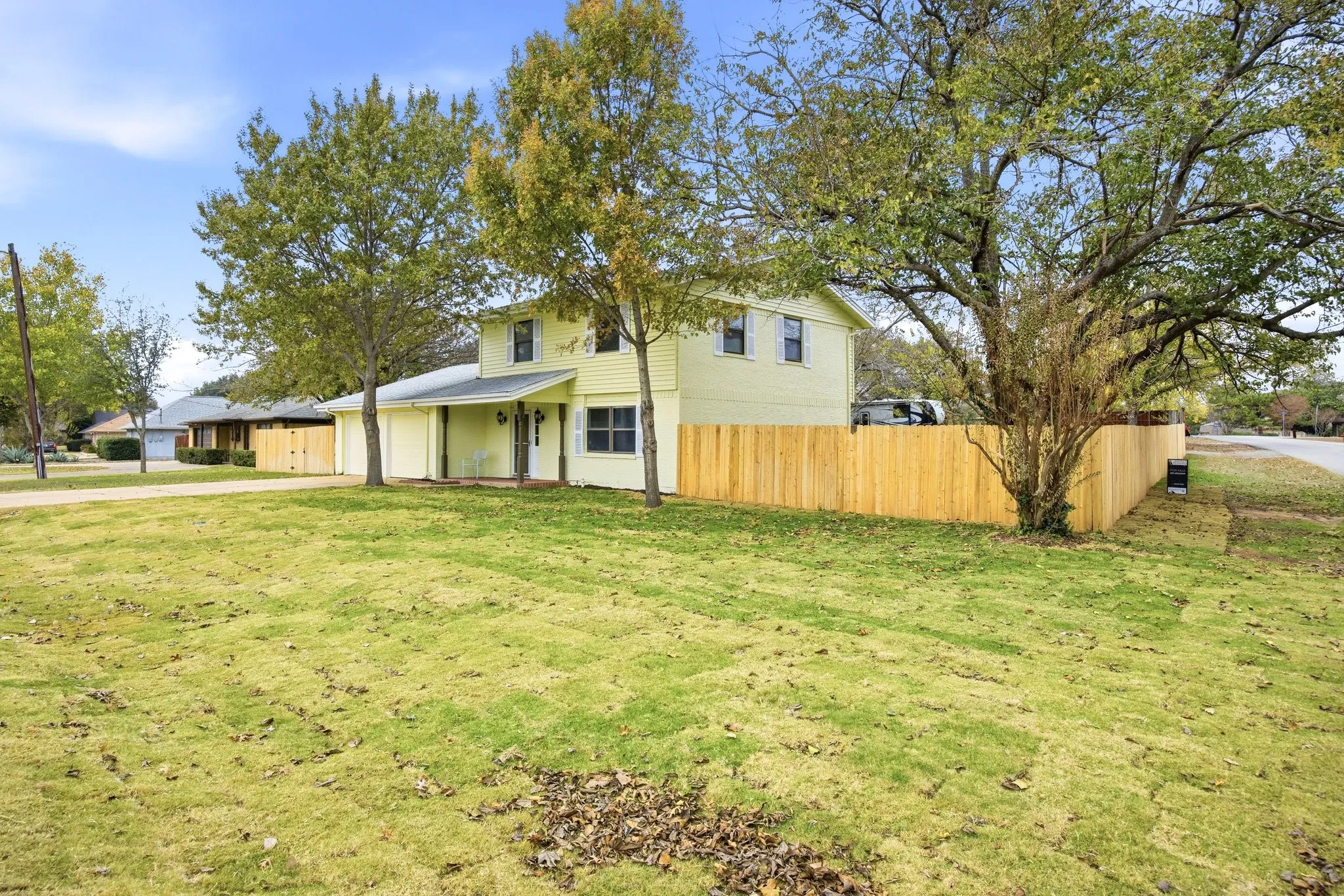 Traditional home featuring covered porch, concrete driveway, and an attached garage, corner lot.
