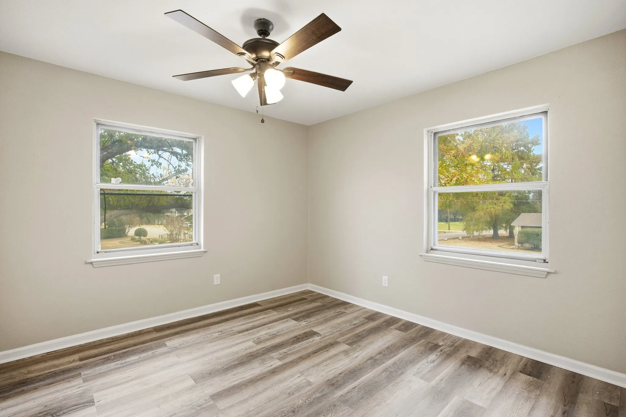 Empty room featuring light wood-style flooring, healthy amount of natural light, and a ceiling fan
