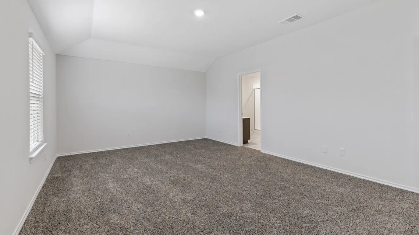 Carpeted spare room featuring vaulted ceiling and baseboards