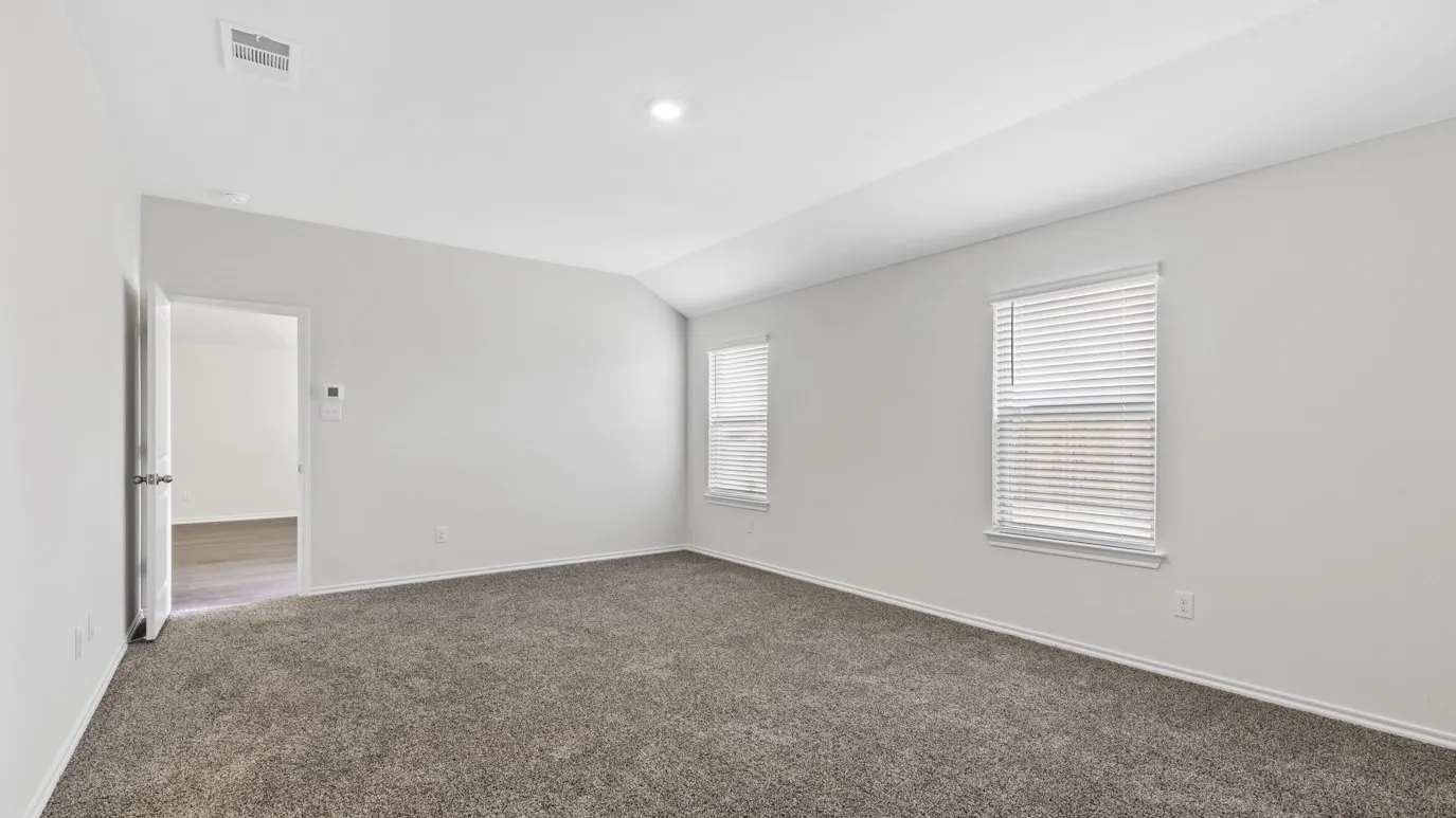 Empty room with dark colored carpet and lofted ceiling