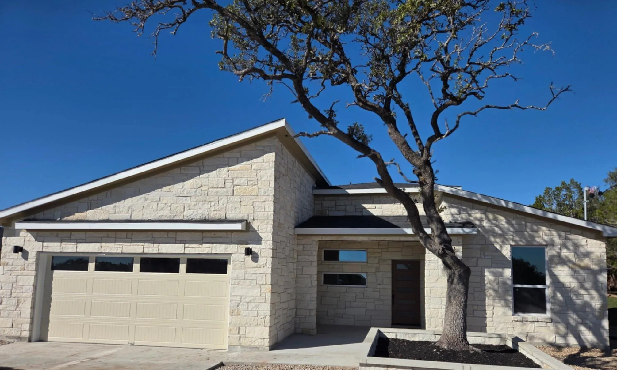 View of front facade with an attached garage, stone siding, and driveway