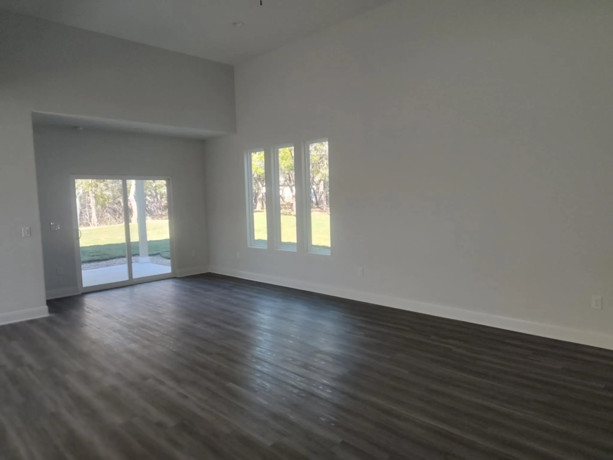Unfurnished room featuring a towering ceiling and dark wood finished floors