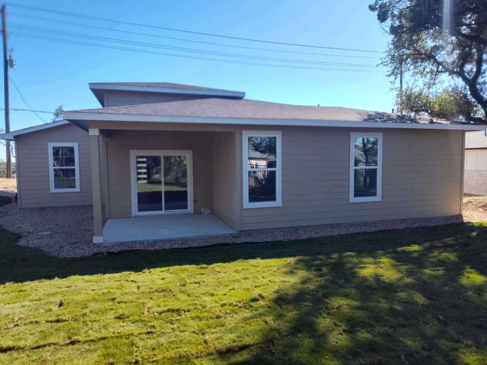 Rear view of property featuring a patio area, a yard, and a shingled roof