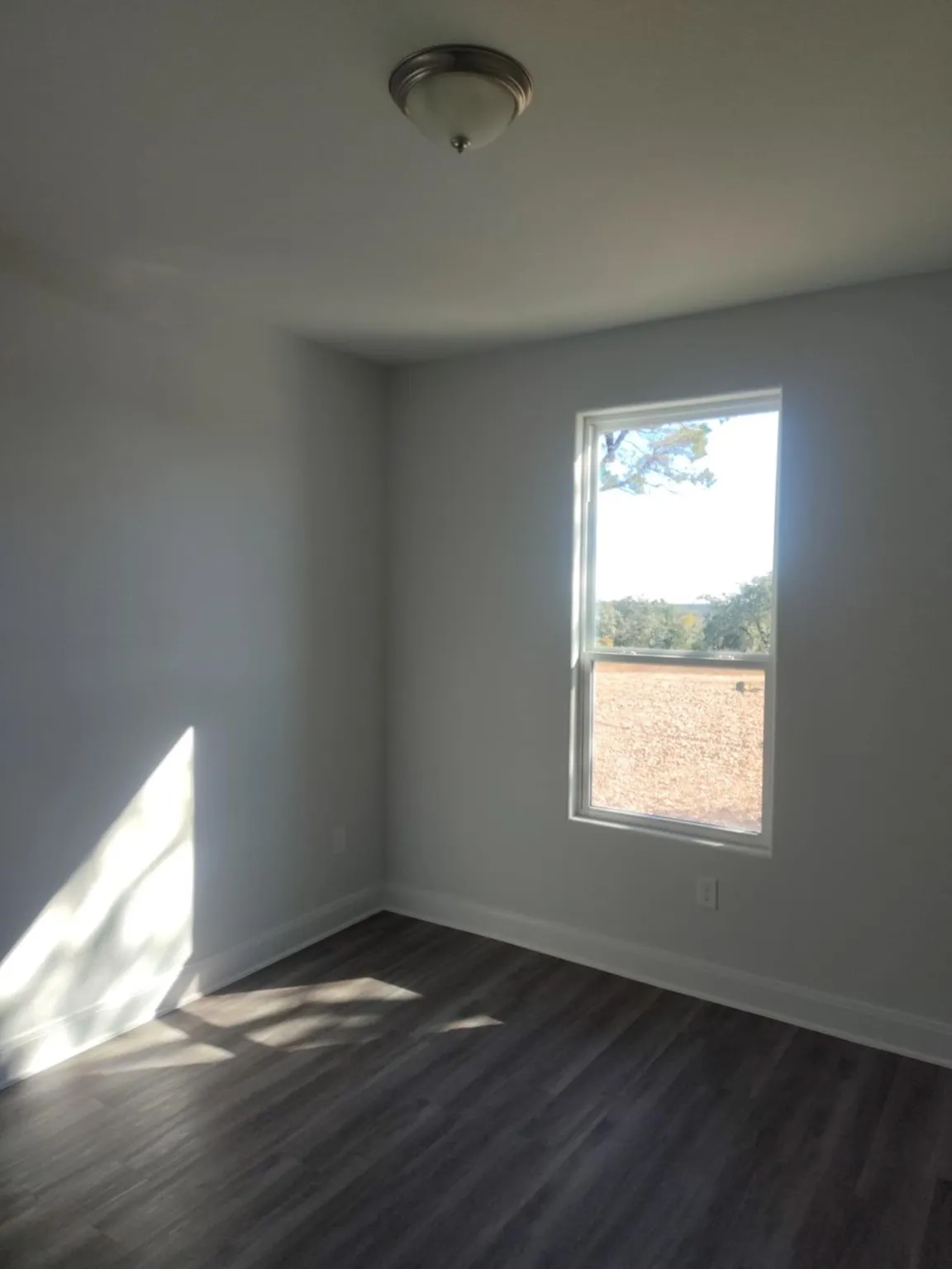Spare room with dark wood-style flooring and baseboards