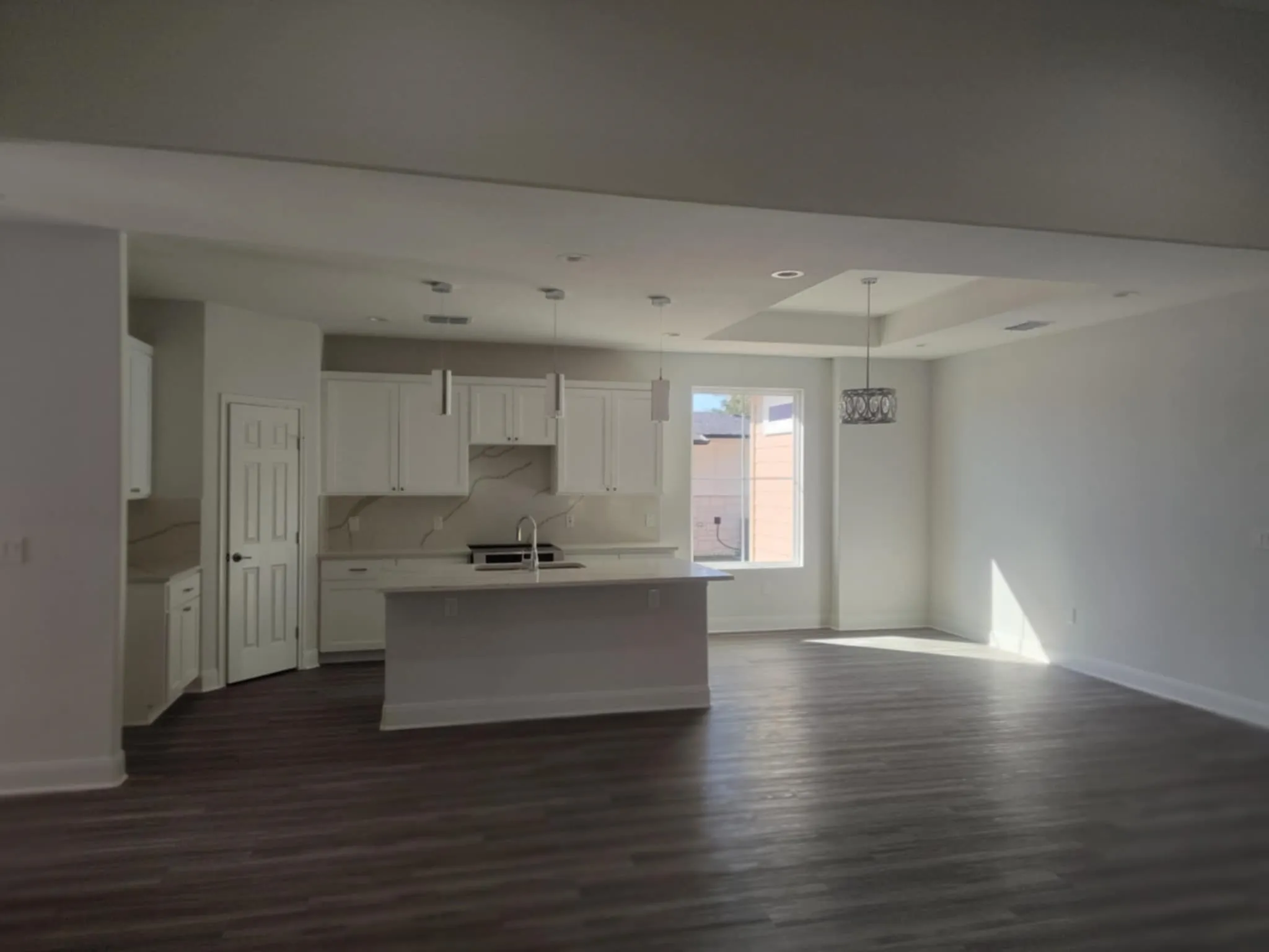 Kitchen featuring white cabinets, decorative light fixtures, a kitchen island with sink, dark wood-style floors, and recessed lighting, Dining Area