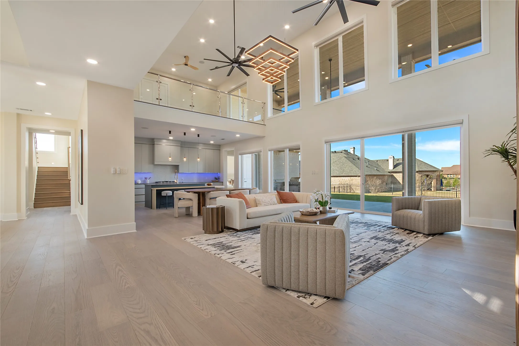 Living area with light wood-style floors, ceiling fan, recessed lighting, stairway, and a towering ceiling