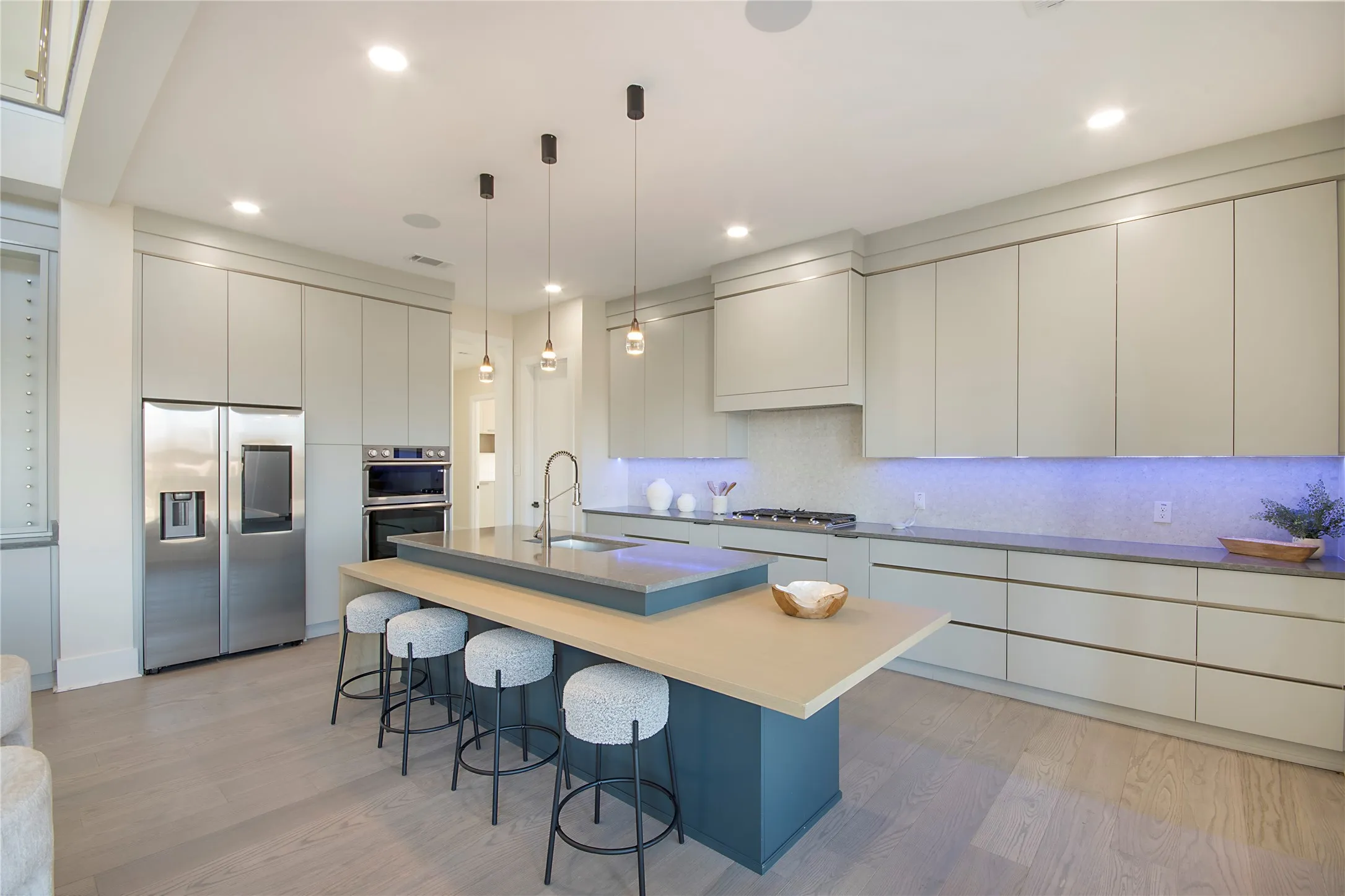 Kitchen with modern cabinets, appliances with stainless steel finishes, pendant lighting, light wood-type flooring, and recessed lighting