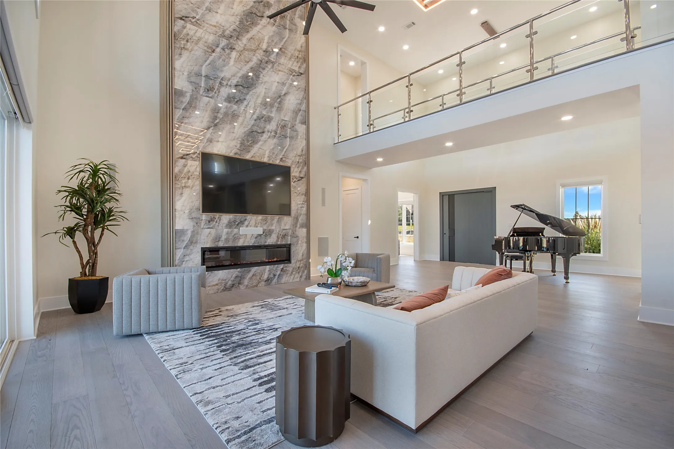 Living area featuring a high end fireplace, wood finished floors, a high ceiling, a ceiling fan, and recessed lighting