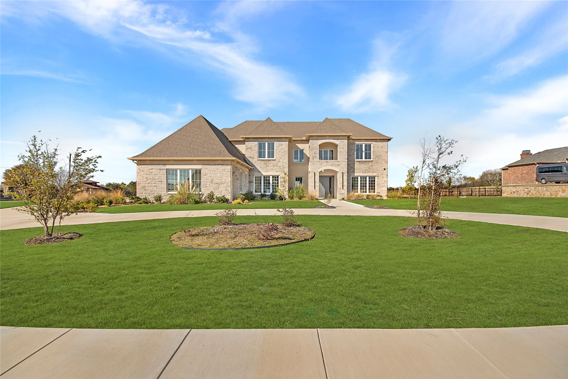 French provincial home featuring curved driveway, a front yard, and brick siding