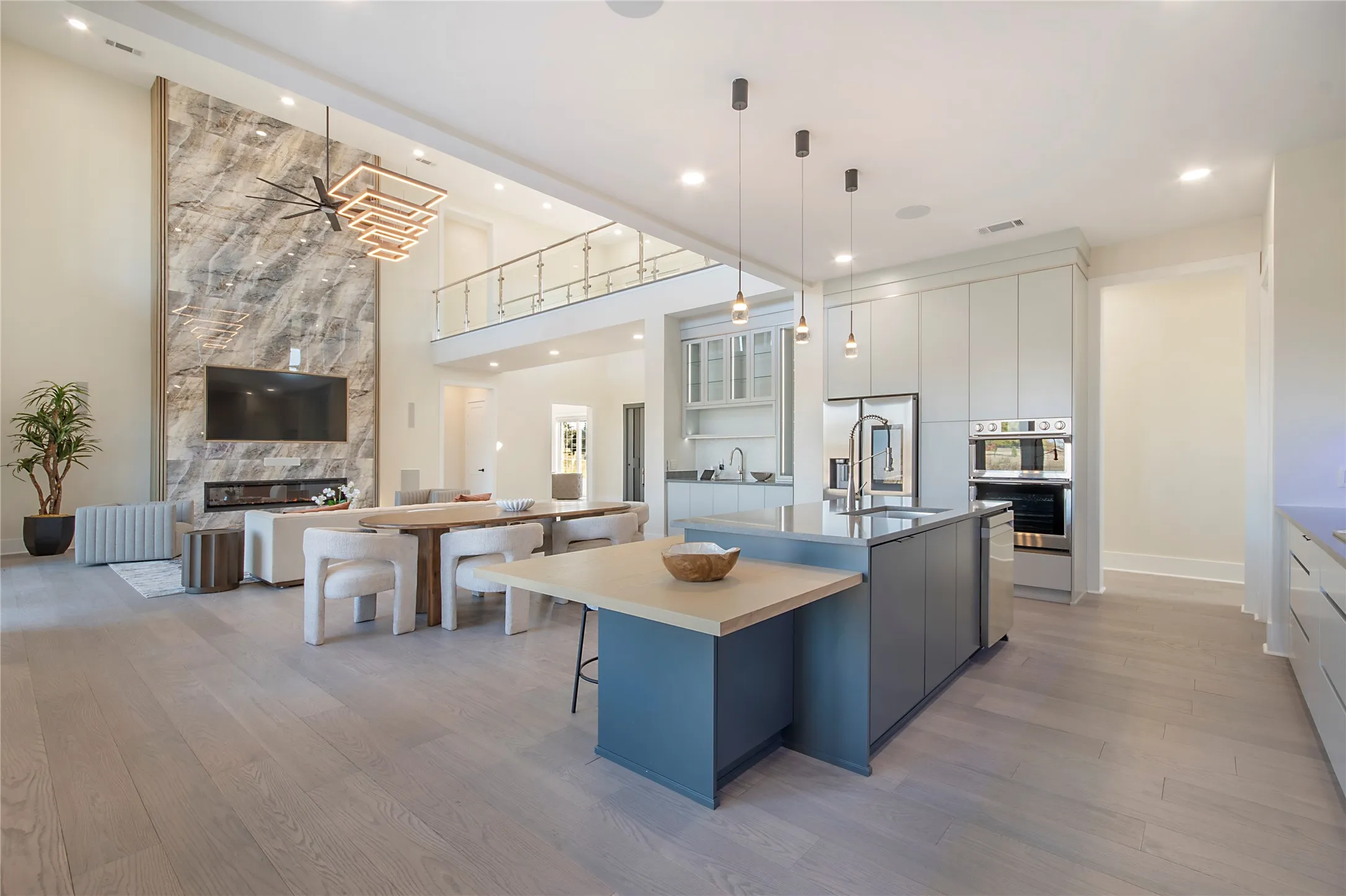 Kitchen with modern cabinets, open floor plan, light wood finished floors, a center island with sink, and a high end fireplace