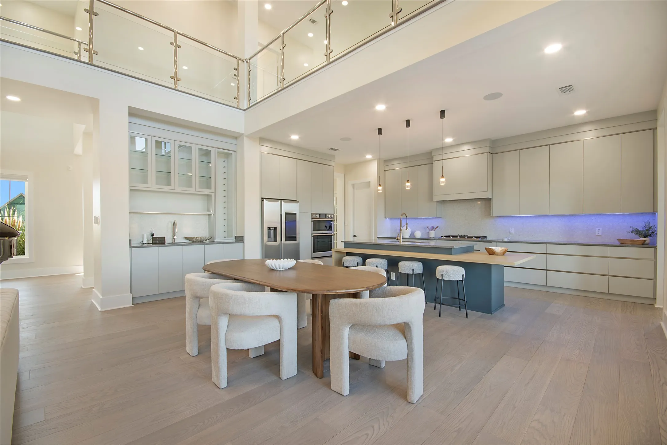 Dining room with light wood-style floors, a towering ceiling, and recessed lighting